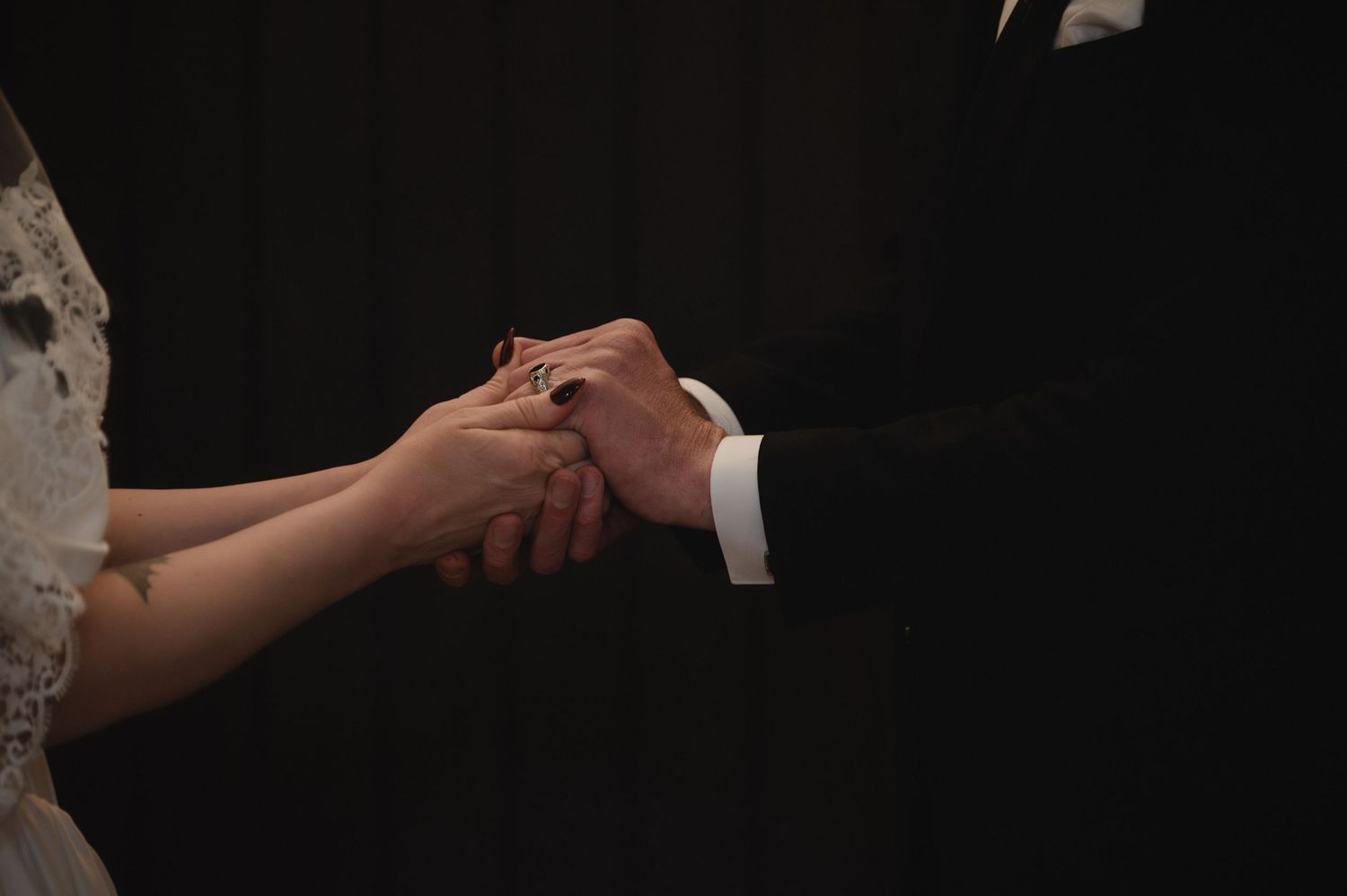 Bride and groom exchanging rings during wedding ceremony, close-up of hands holding together.