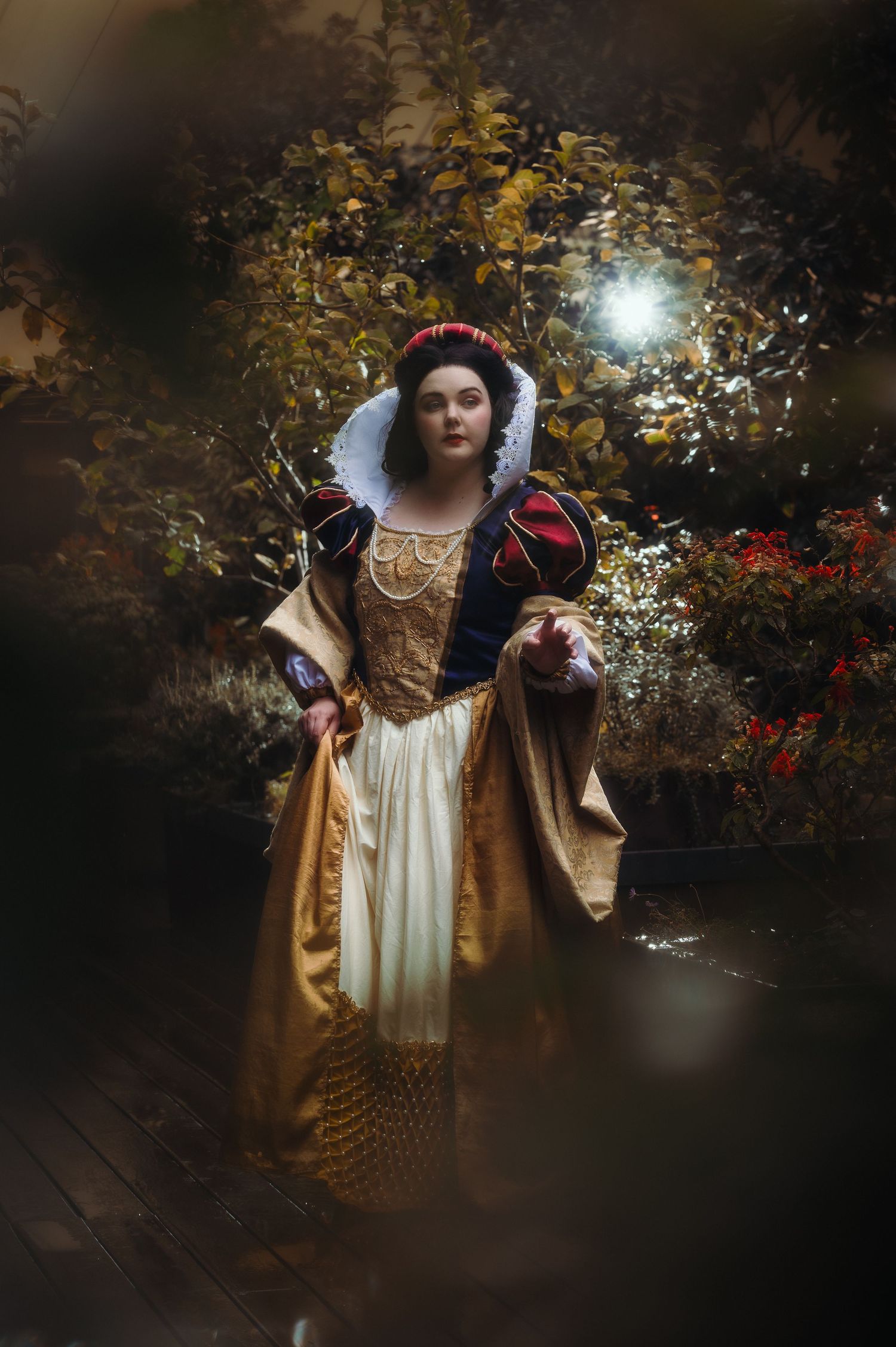 Renaissance style portrait in ornate gold dress against dark forest backdrop.
