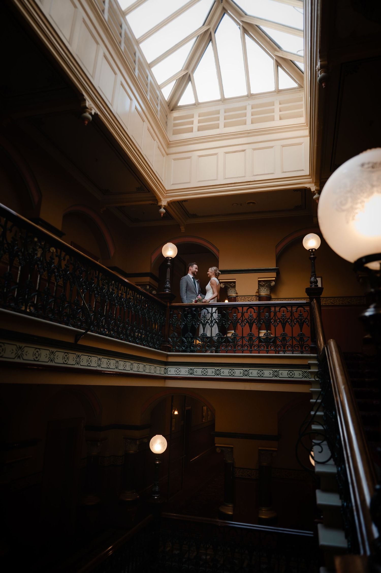 Dramatic skylight illuminates a grand staircase with ornate railings in a historic building.
