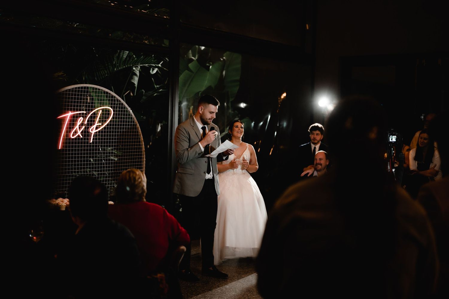 Wedding guests dancing and celebrating on a dimly lit dance floor at a reception party.