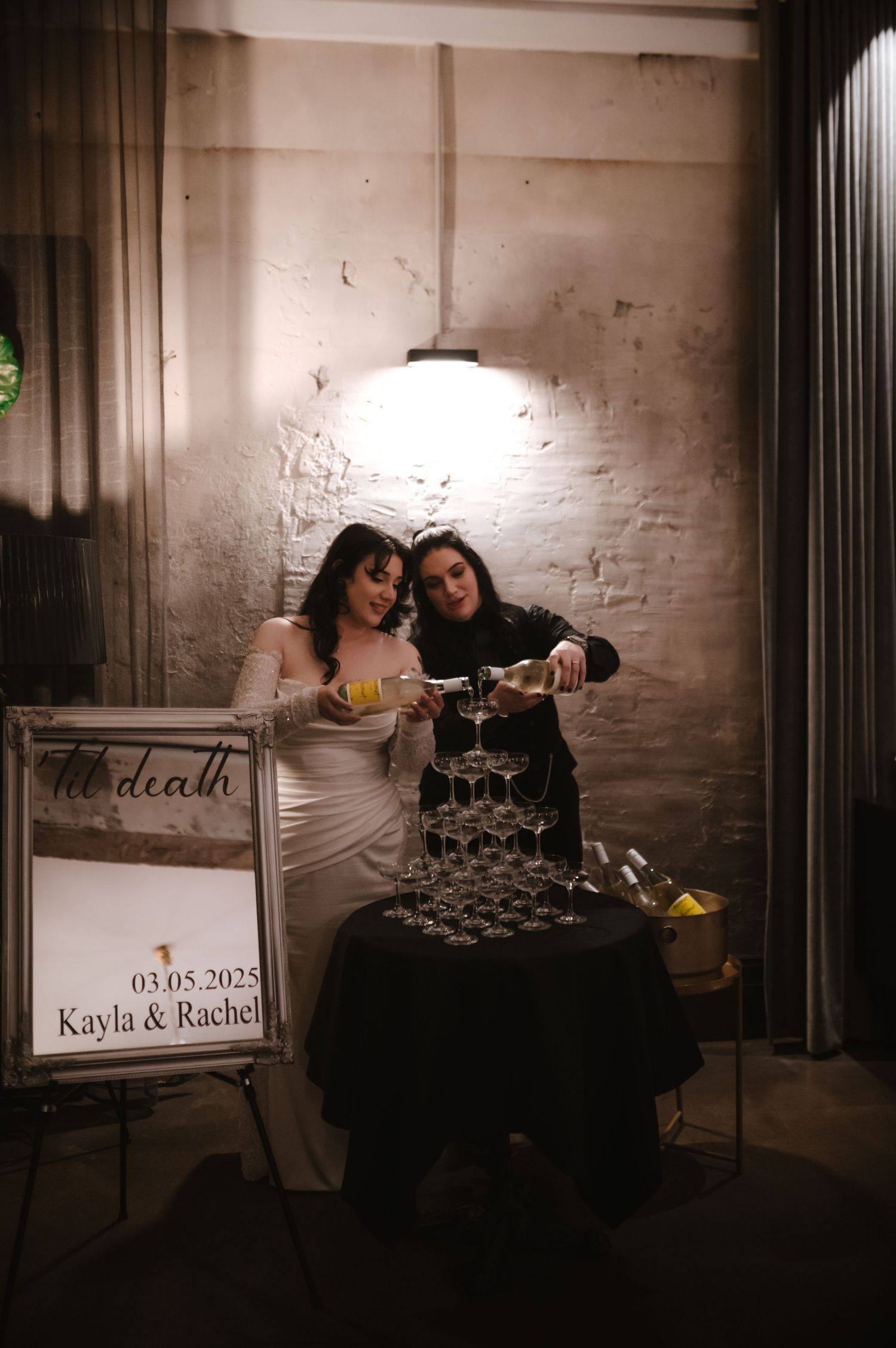A wedding reception setup with signage and decorations in an industrial-style venue.