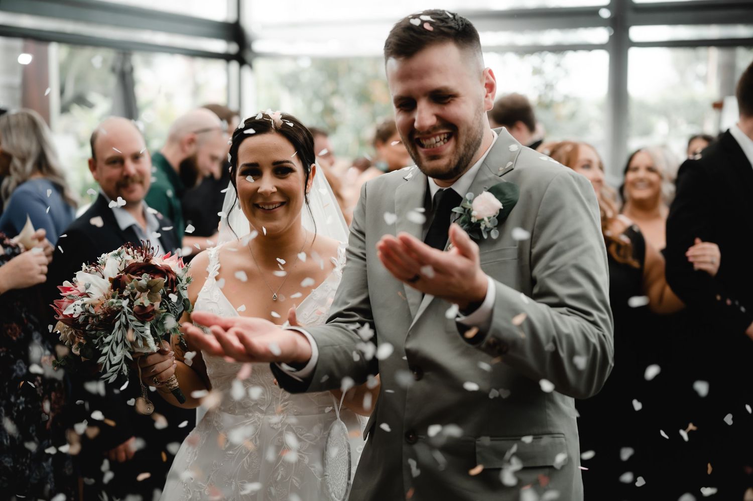 Joyful wedding celebration with confetti flying through the air in an indoor venue.