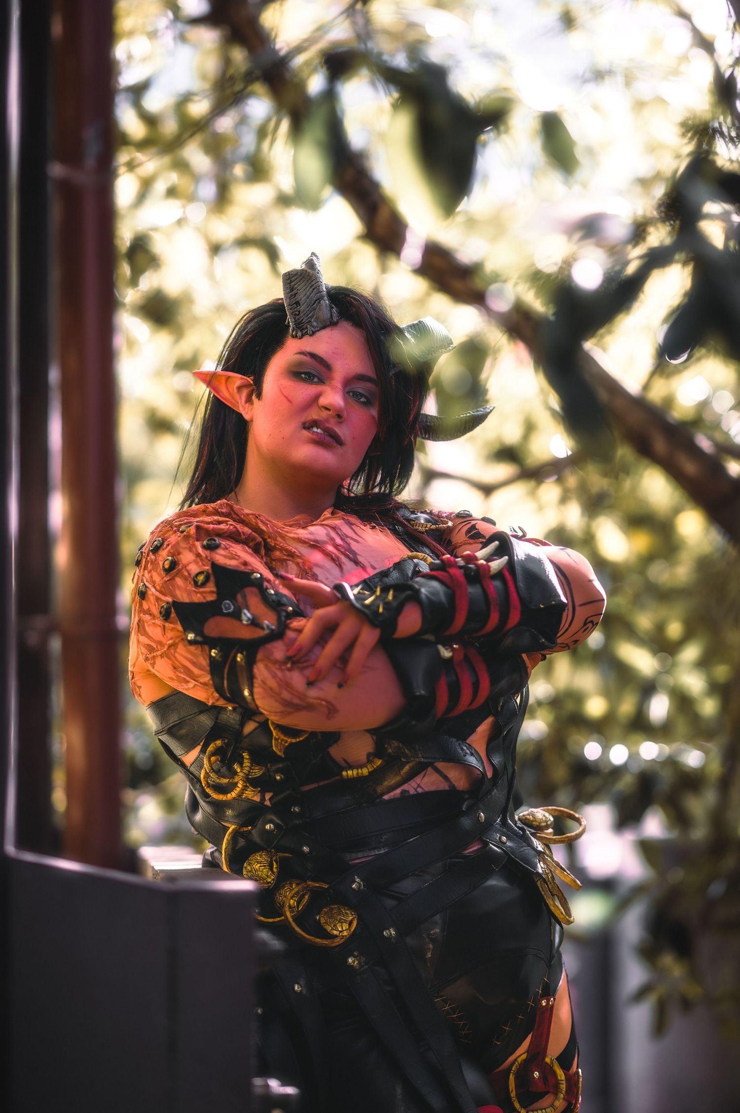 Fantasy costume photoshoot with ornate red and gold details in natural lighting.