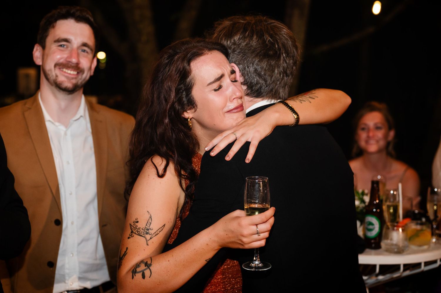 Wedding reception celebration with guests dancing and enjoying drinks in a dimly lit venue.