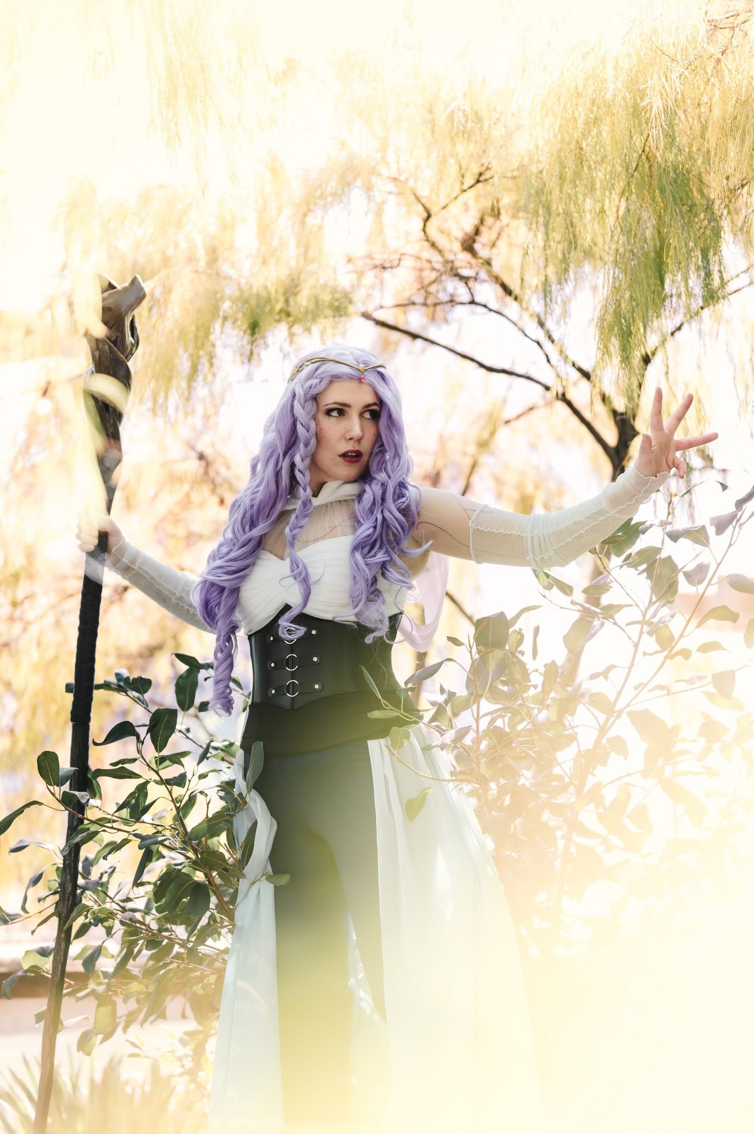 Fantasy-themed outdoor portrait with lavender hair against a sunlit natural backdrop.