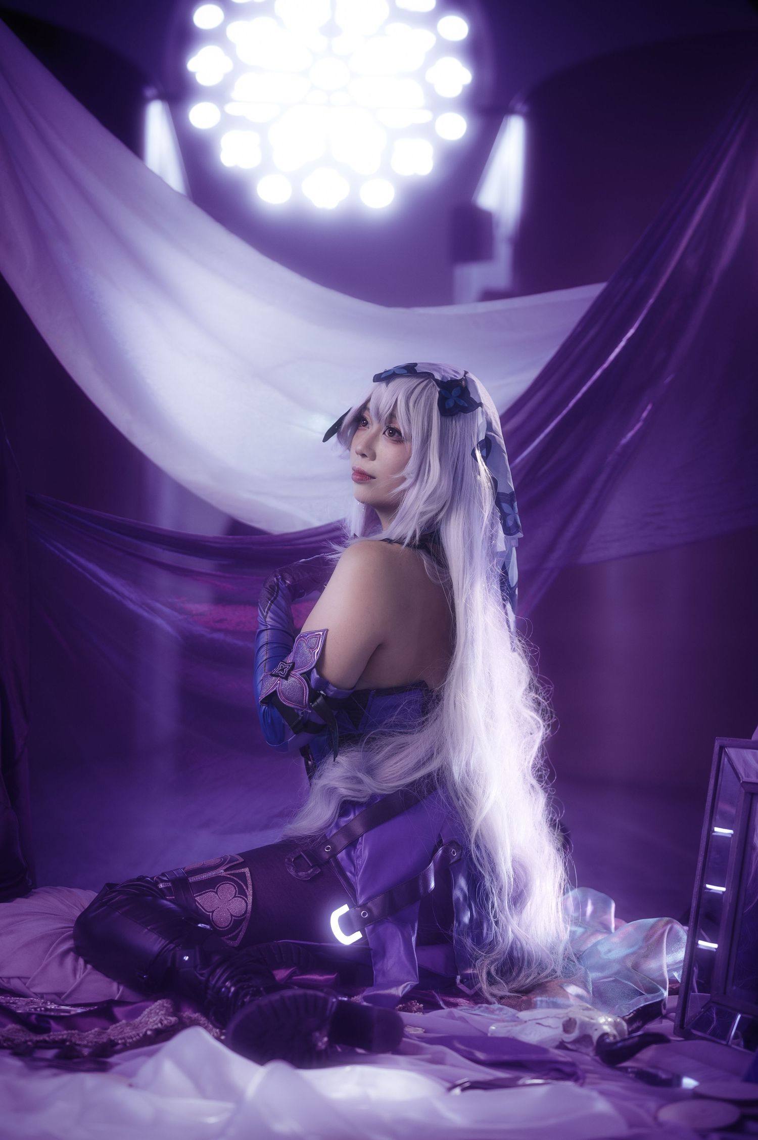 Ethereal portrait with flowing white fabric and dramatic purple stage lighting.