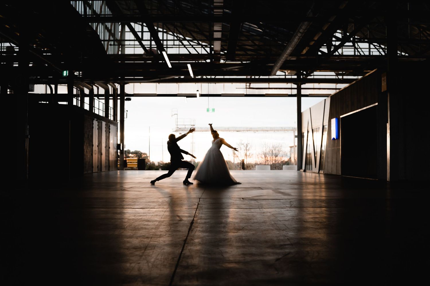Silhouettes dance and pose dramatically in empty industrial space.