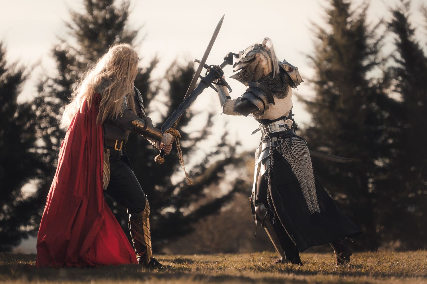 Dramatic sword fight scene between figures in medieval costumes against evergreen trees.