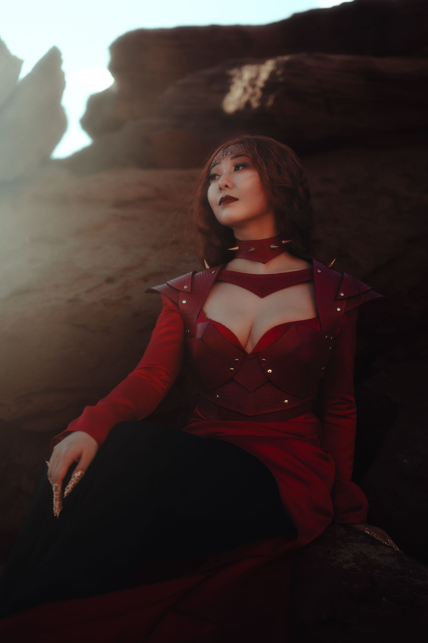 Atmospheric portrait in deep red tones against dramatic cave lighting.