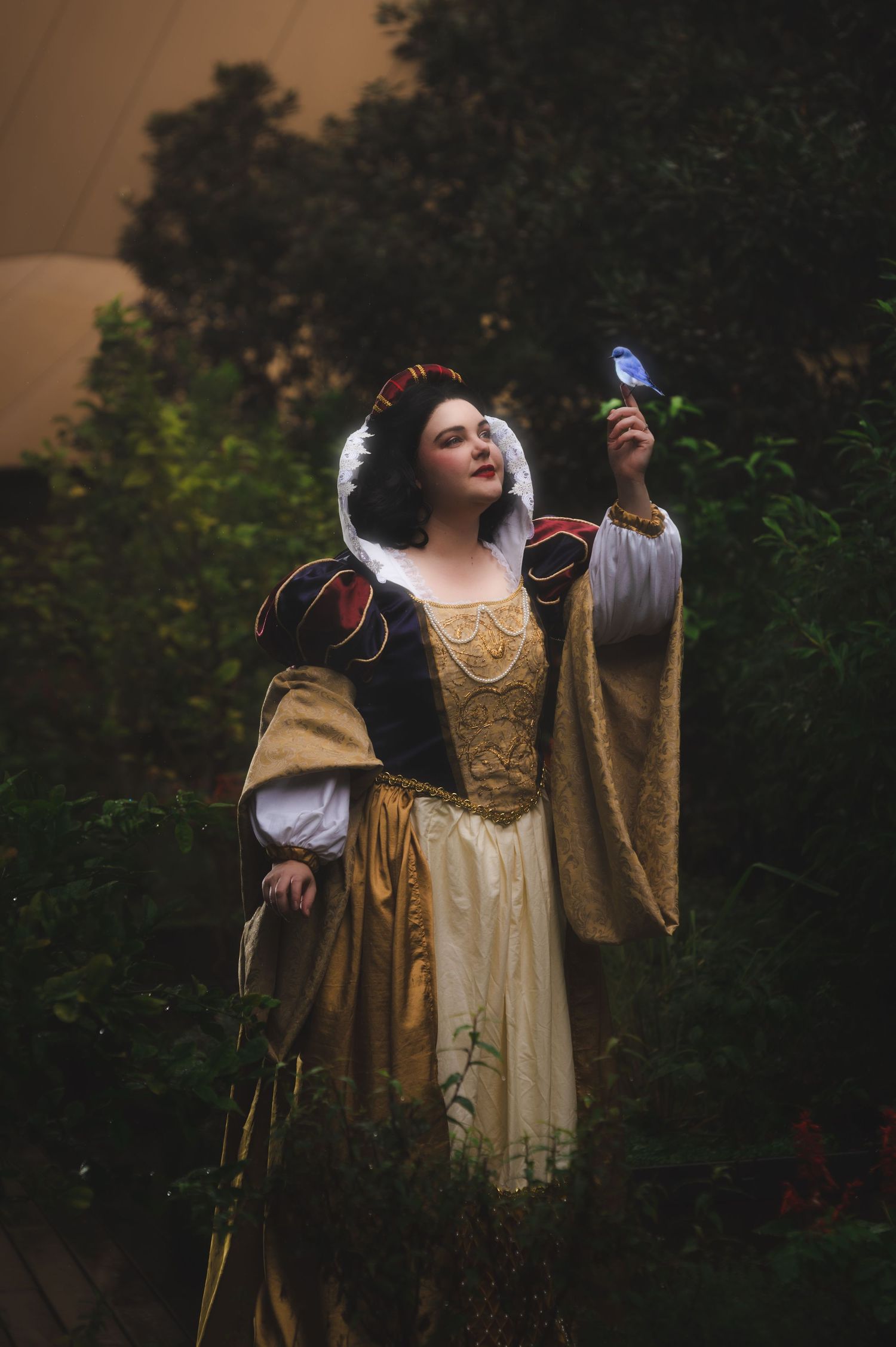 Fairytale themed portrait with blue bird in enchanted garden setting.