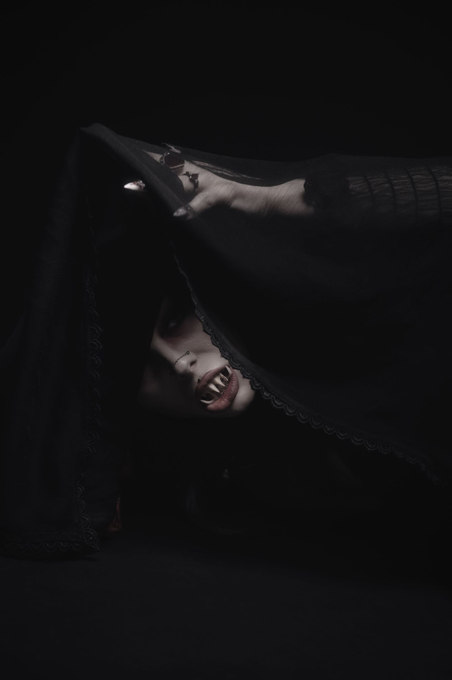 Dramatic black and white portrait with outstretched arms in dark shadows.