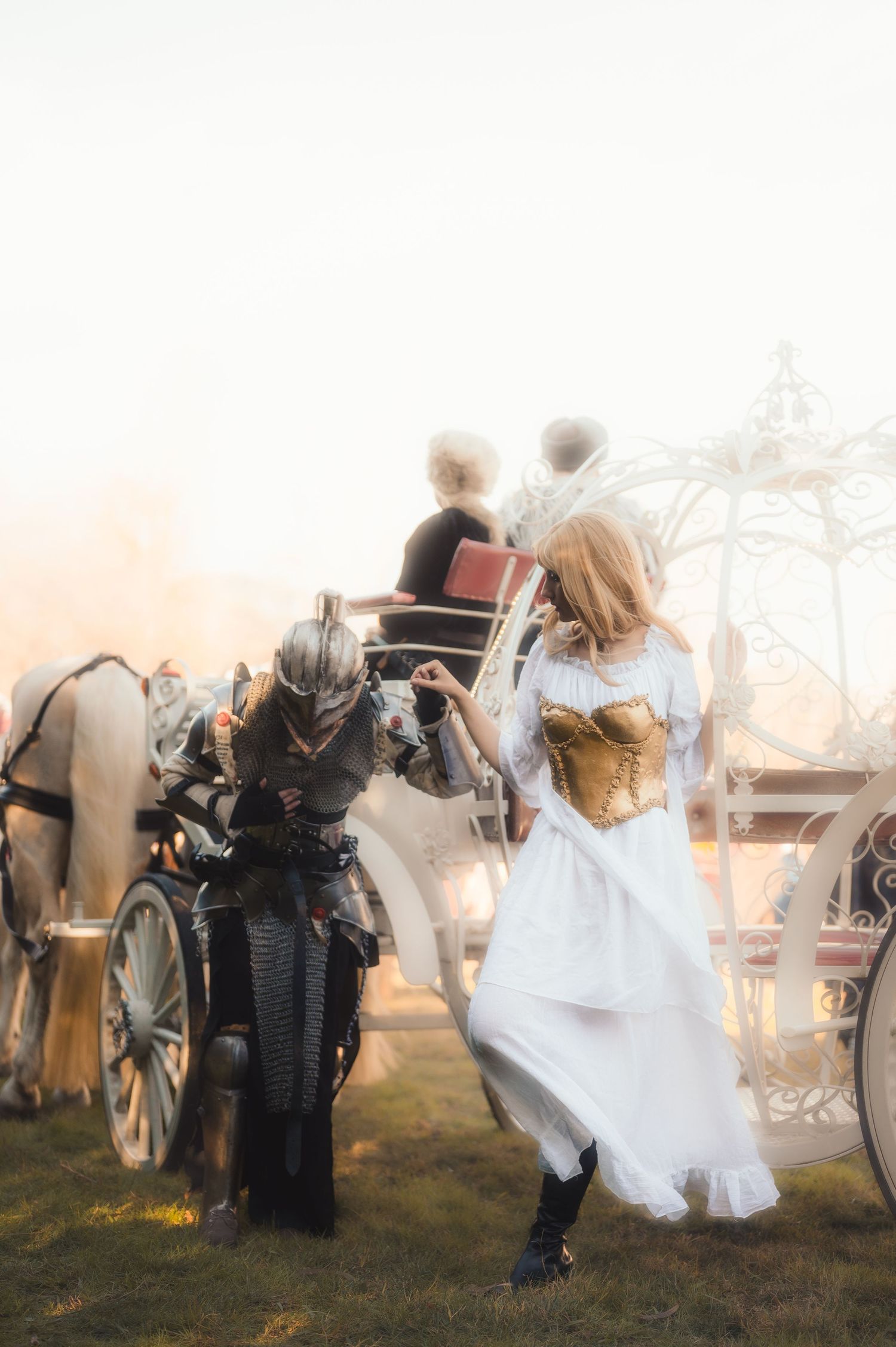 Medieval-themed photoshoot with horse-drawn carriage and flowing white dress in golden sunset light.
