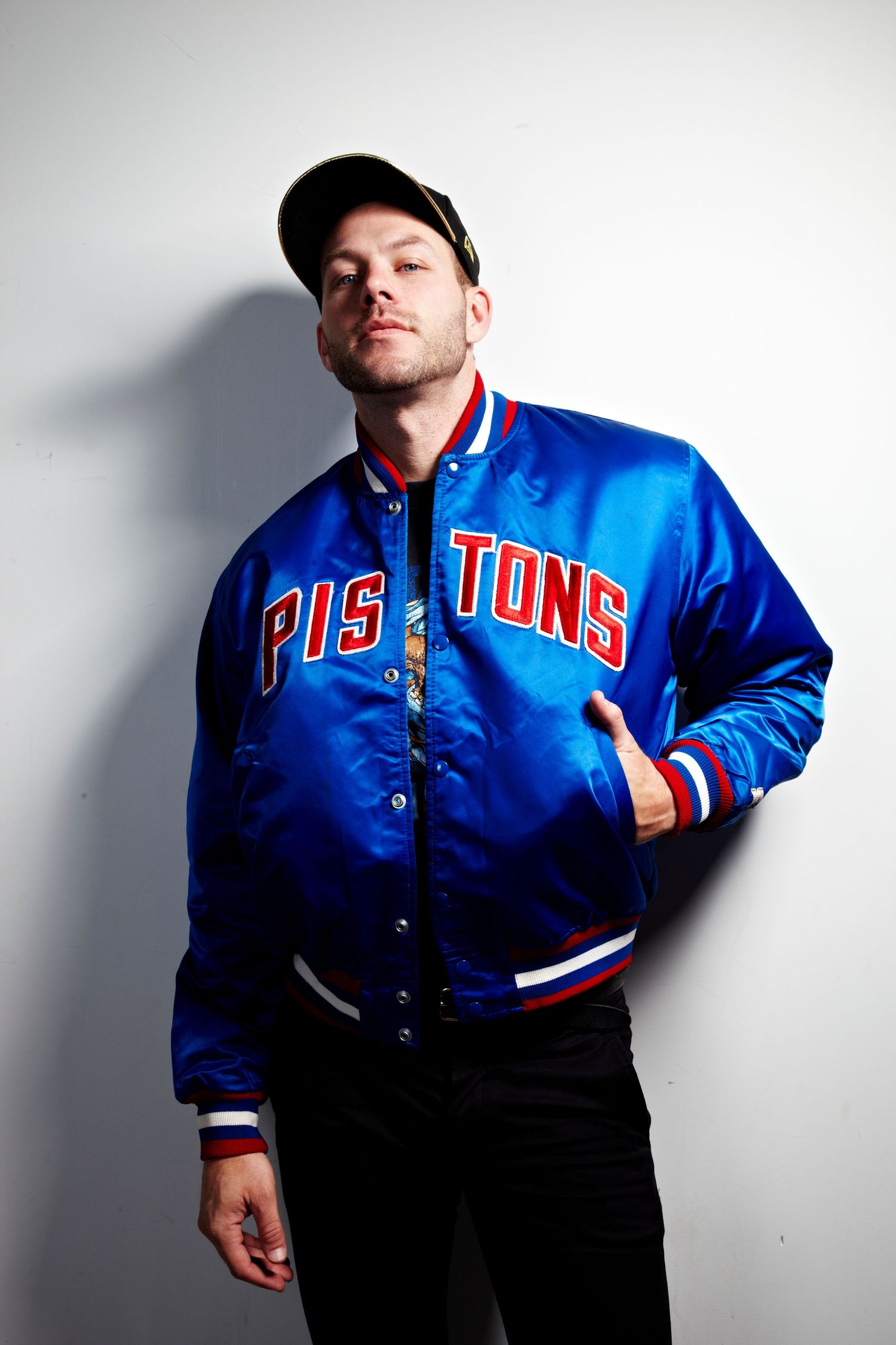Someone poses in a Detroit Pistons blue and red varsity jacket against a white background.