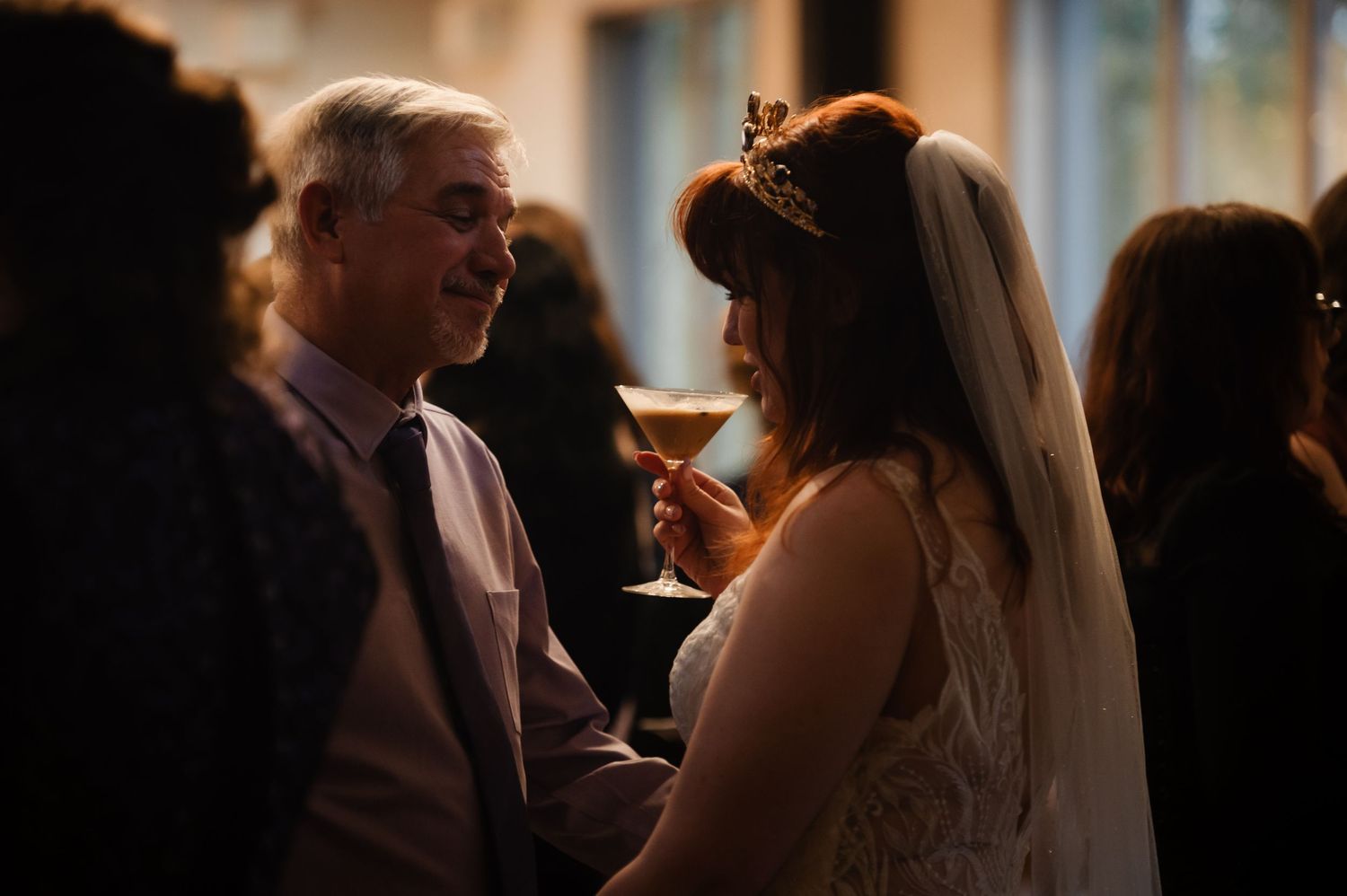 Wedding reception guests mingle in warm lighting during evening celebration.
