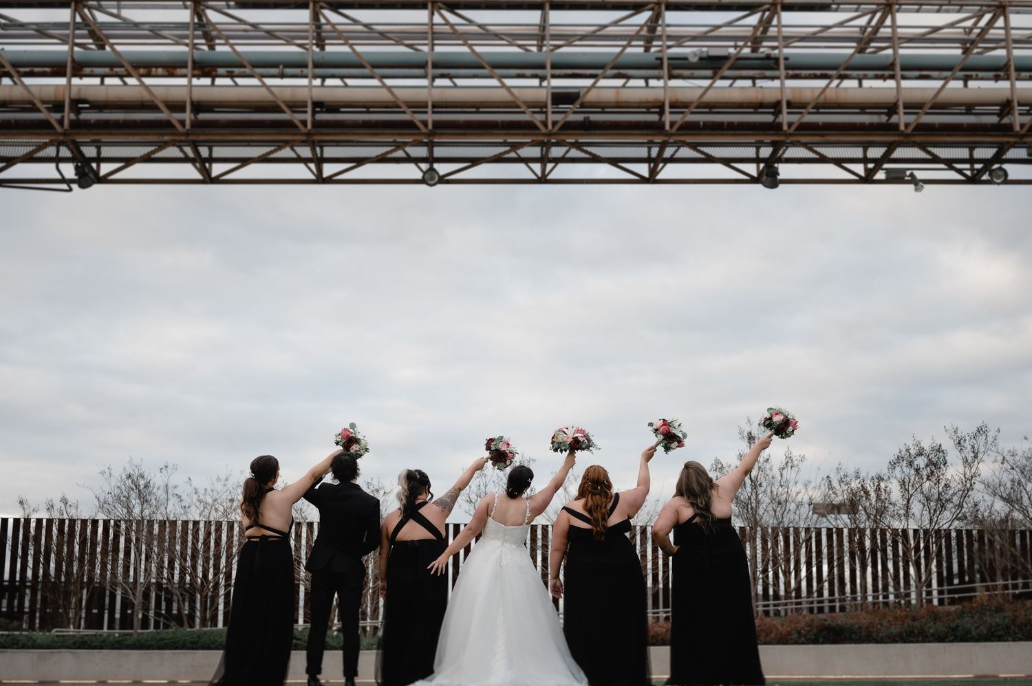 Wedding party poses creatively on rooftop with urban skyline in background.