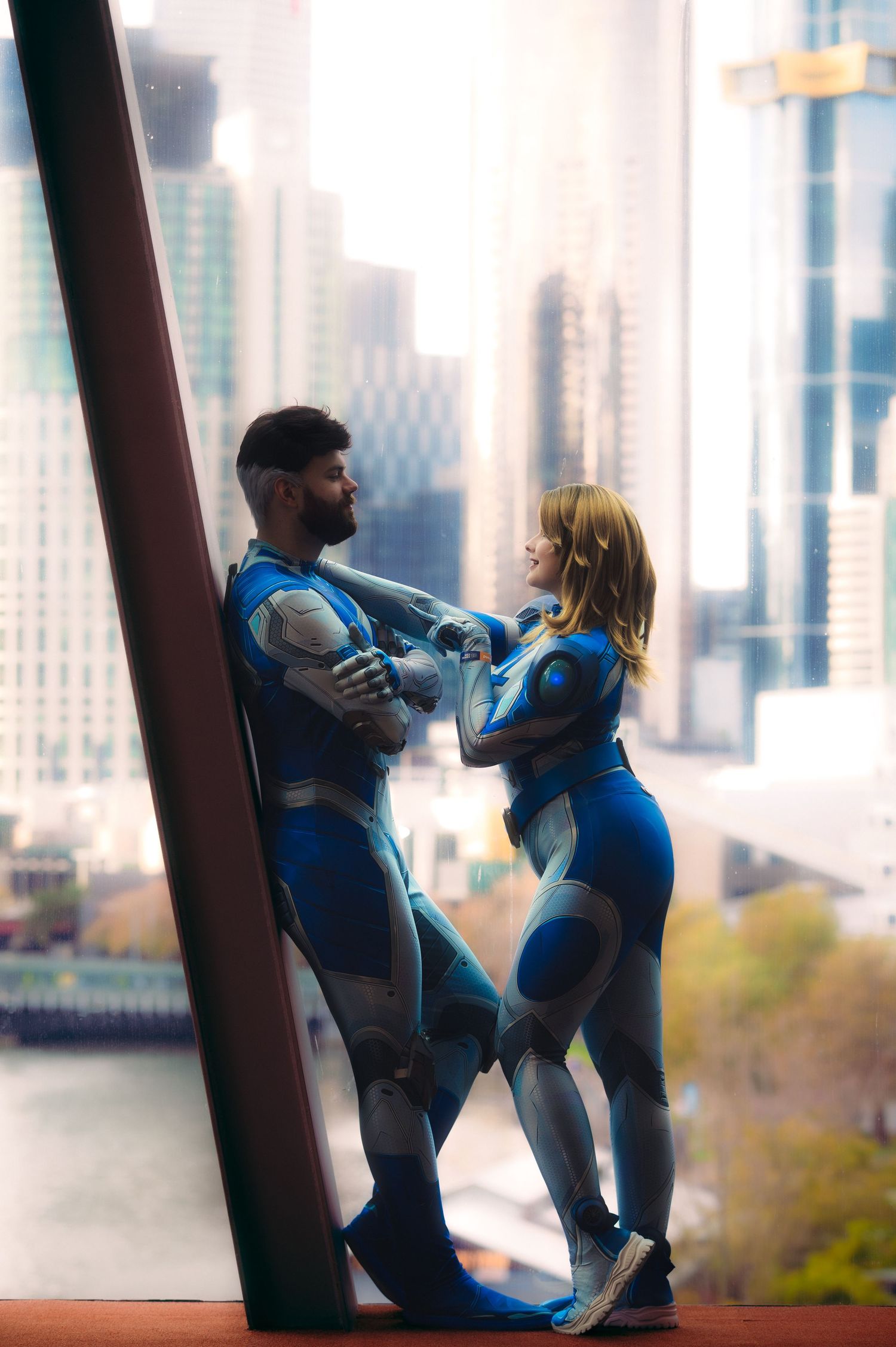 Costumed figures pose against an urban skyline backdrop with tall buildings.