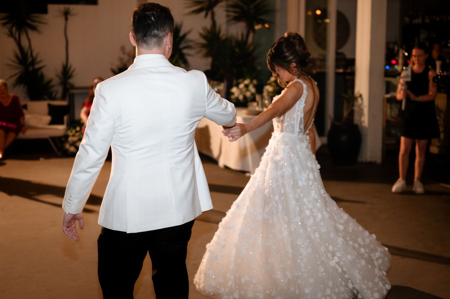 Newlyweds dancing together at their wedding reception with decorative lights in the background.