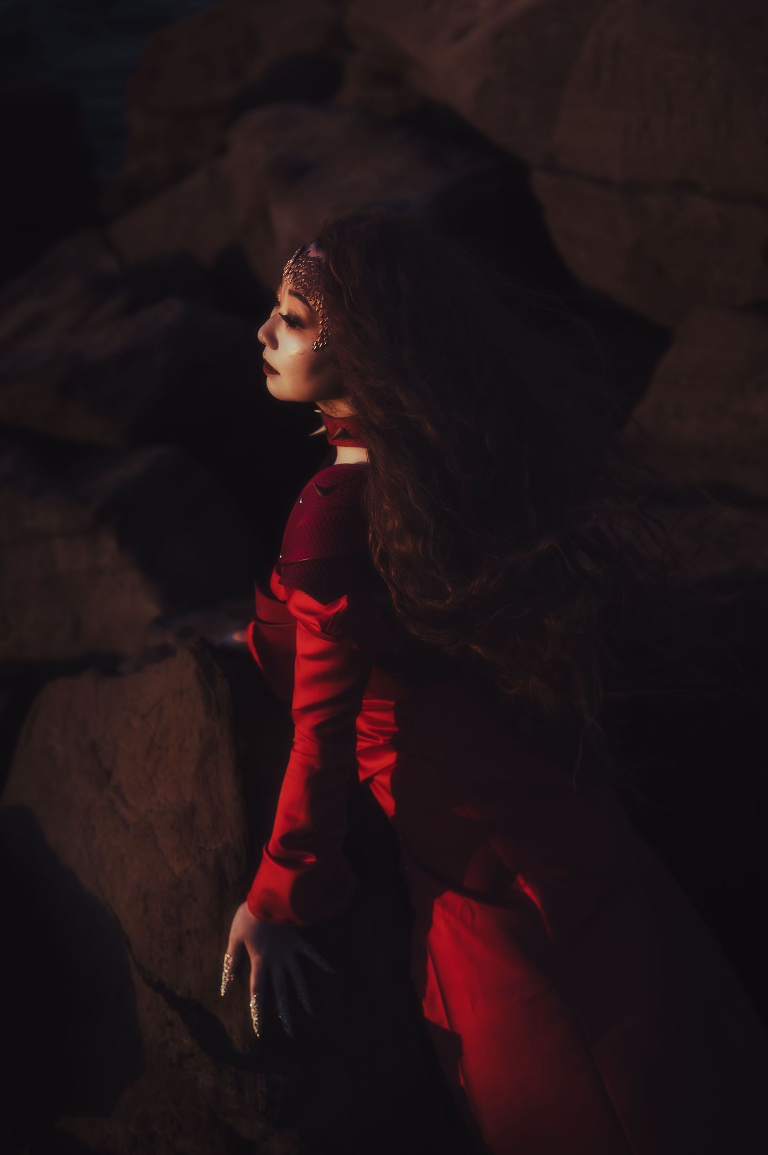 Dramatic portrait in red dress against dark moody background.