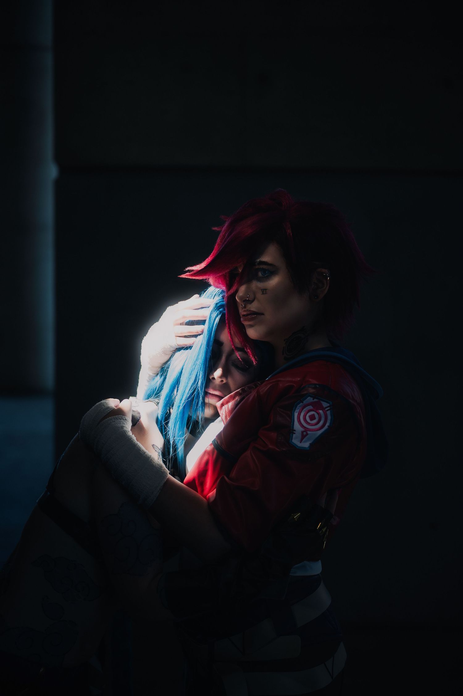 Moody portrait with dramatic lighting and colorful hair in dark setting.