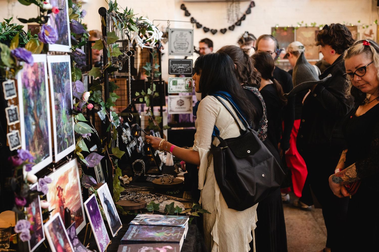 Crowded art gallery event showing visitors browsing displayed artwork and photographs along walls.