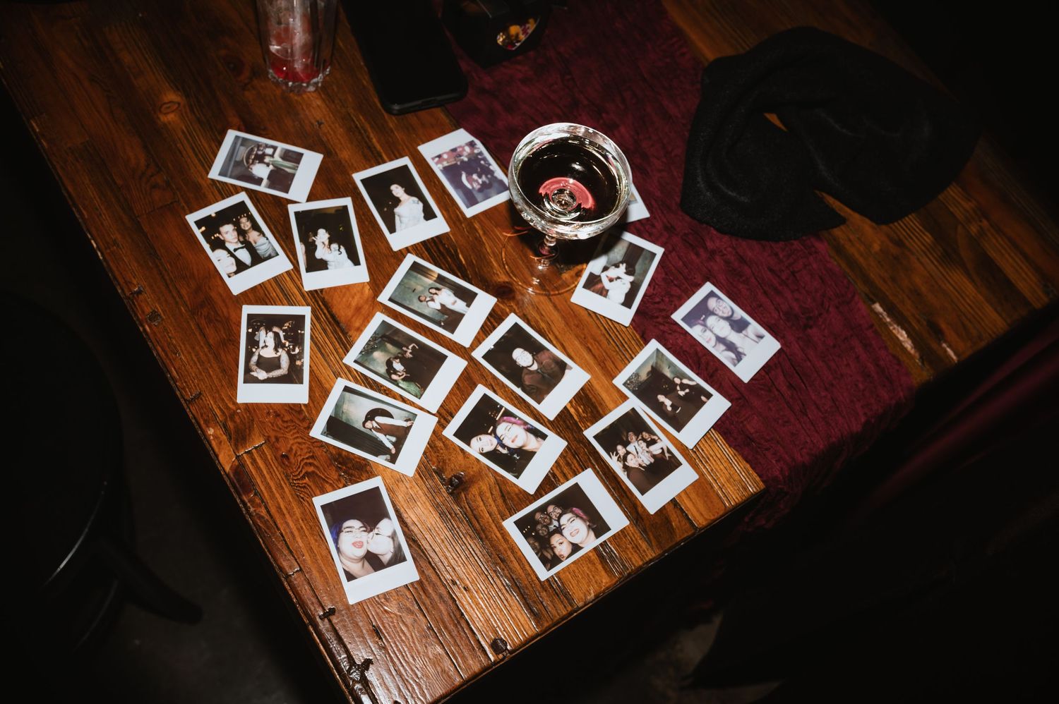 Polaroid photos scattered across a wooden table surface at an event.