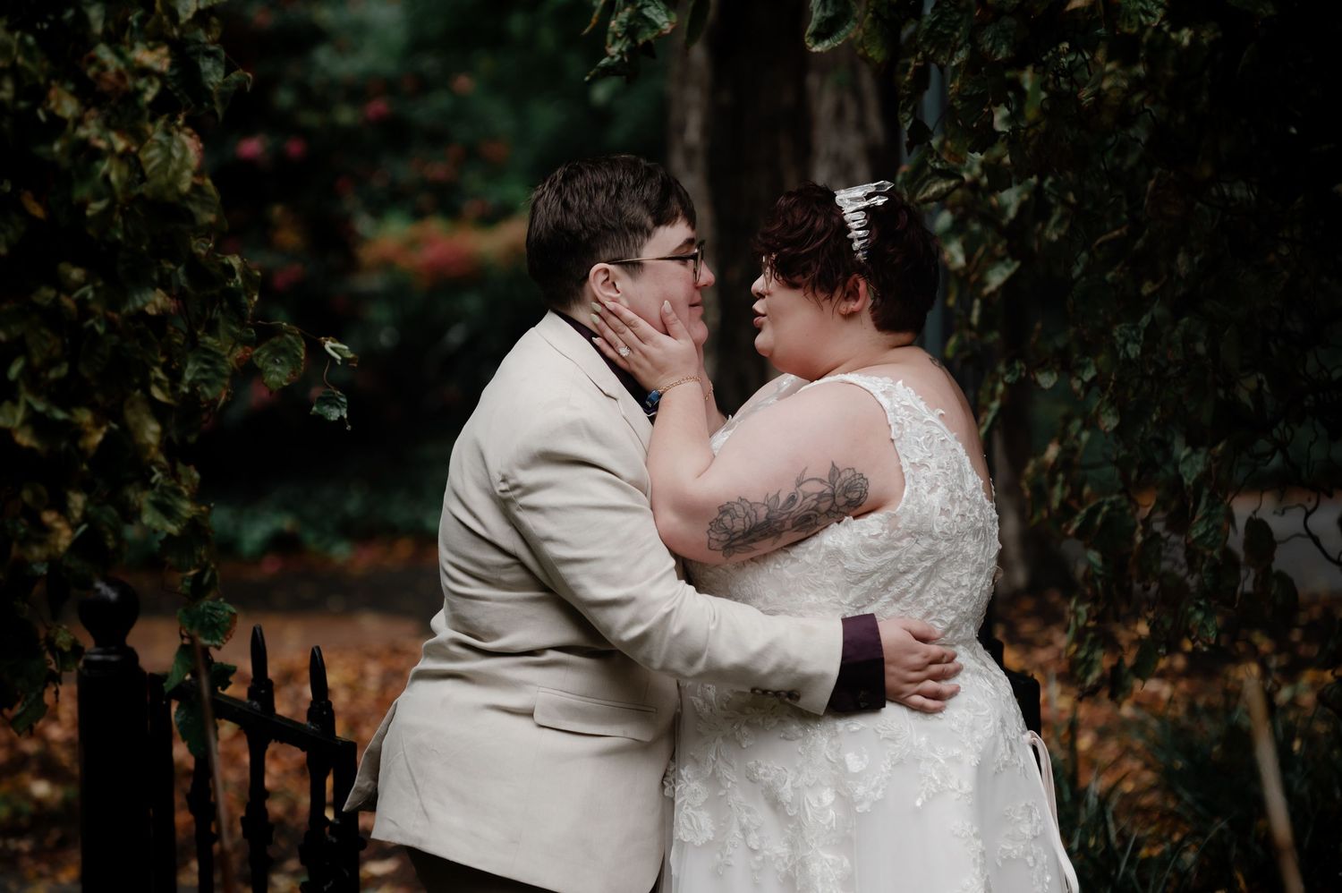 A romantic wedding moment captured in a garden setting with two people in white and cream attire embracing.