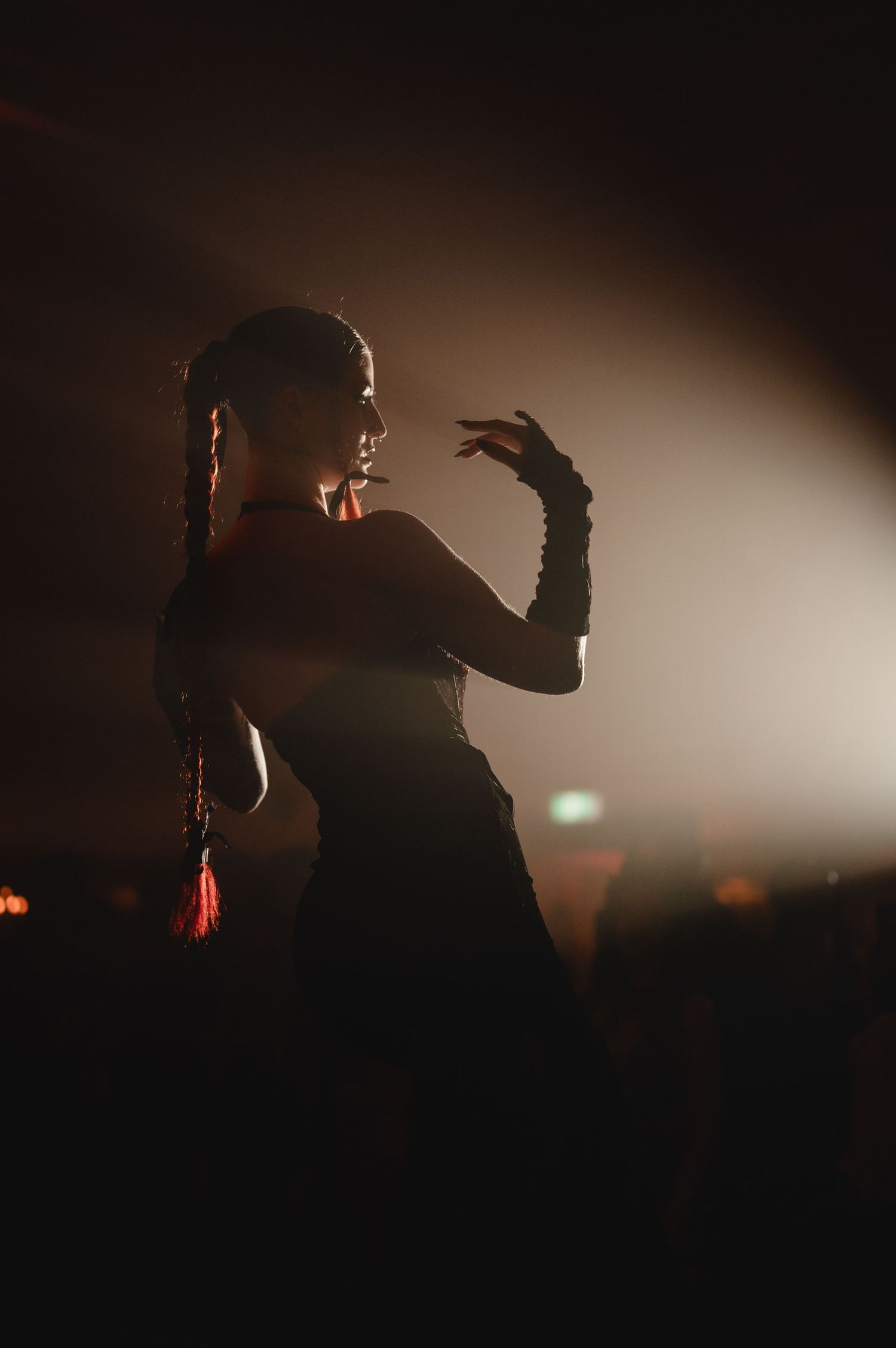 Silhouetted figures performing on a dimly lit stage with atmospheric backlighting creating dramatic shadows.
