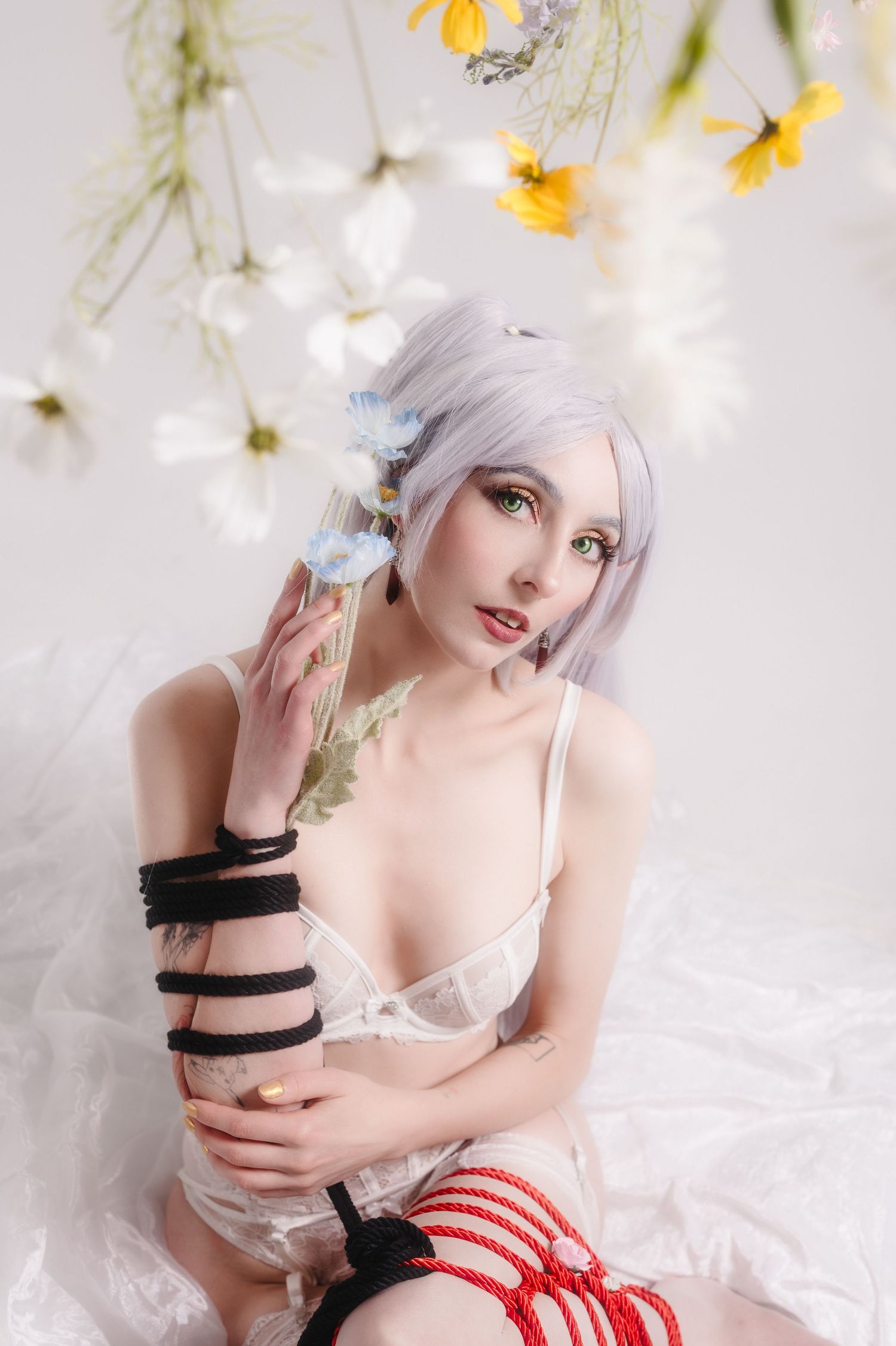 Artistic fashion portrait with white flowers, red and white striped fabric, and ethereal lighting effects.