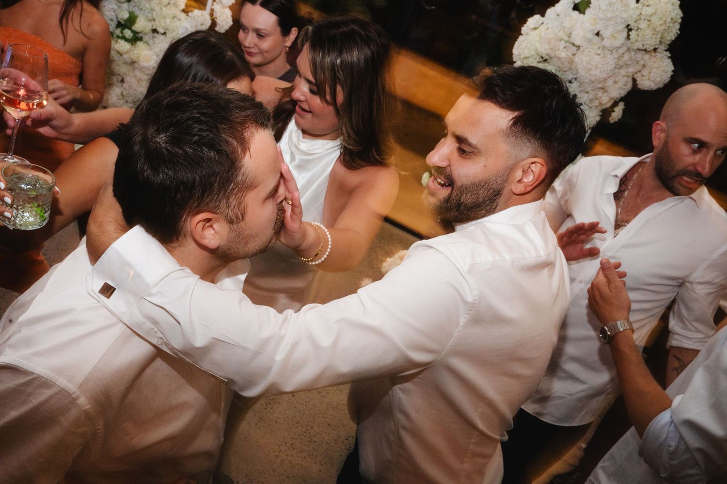 Wedding celebration with guests dancing energetically under warm lighting.