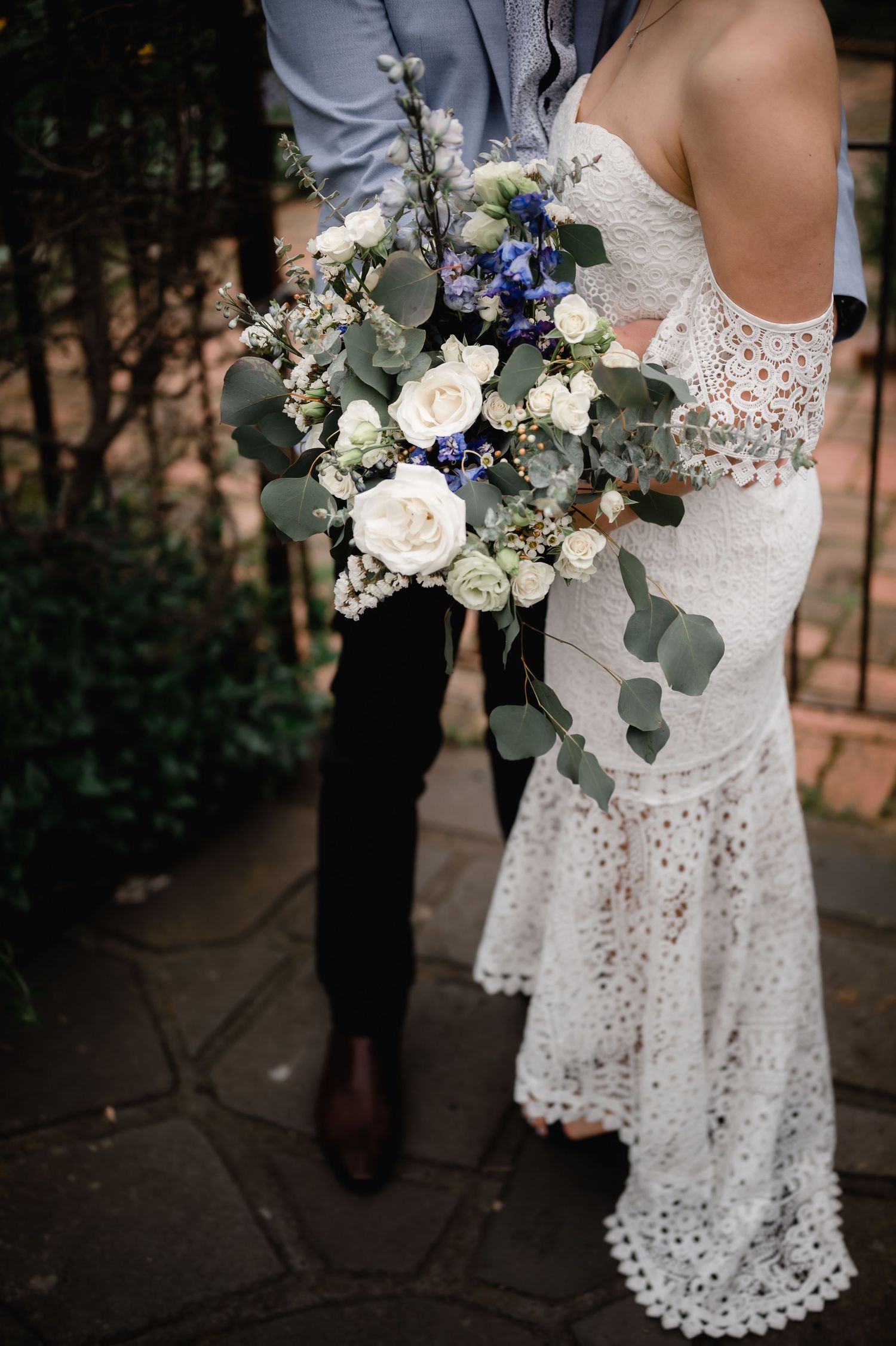 Close-up of an elegant white and blue wedding bouquet with eucalyptus leaves.