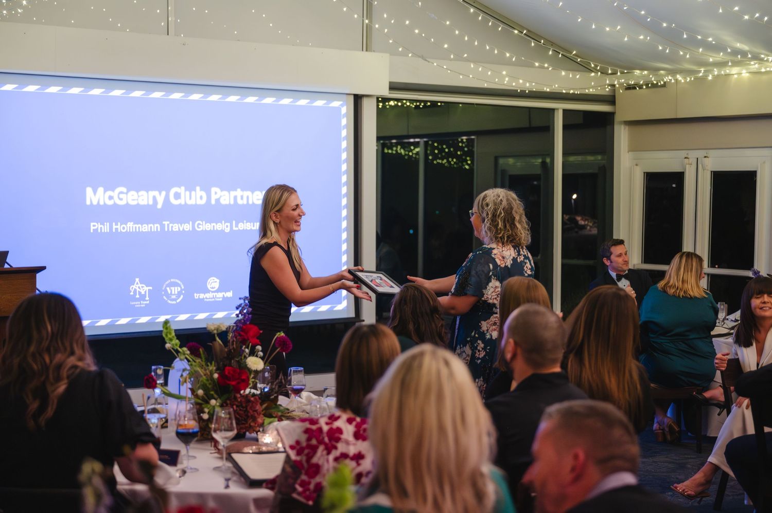 Award ceremony at McGeary Club Partner event with guests dining at decorated tables while presenter addresses the audience.