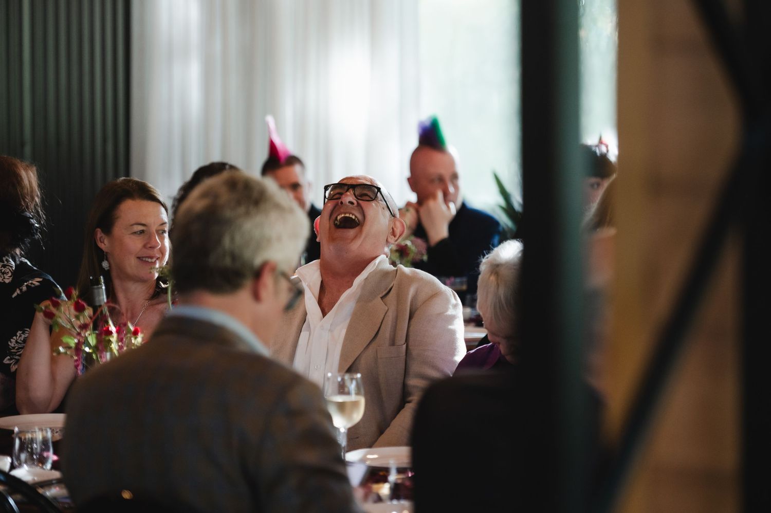 A group of people gathered at a restaurant table share laughter and conversation during a social dining experience.