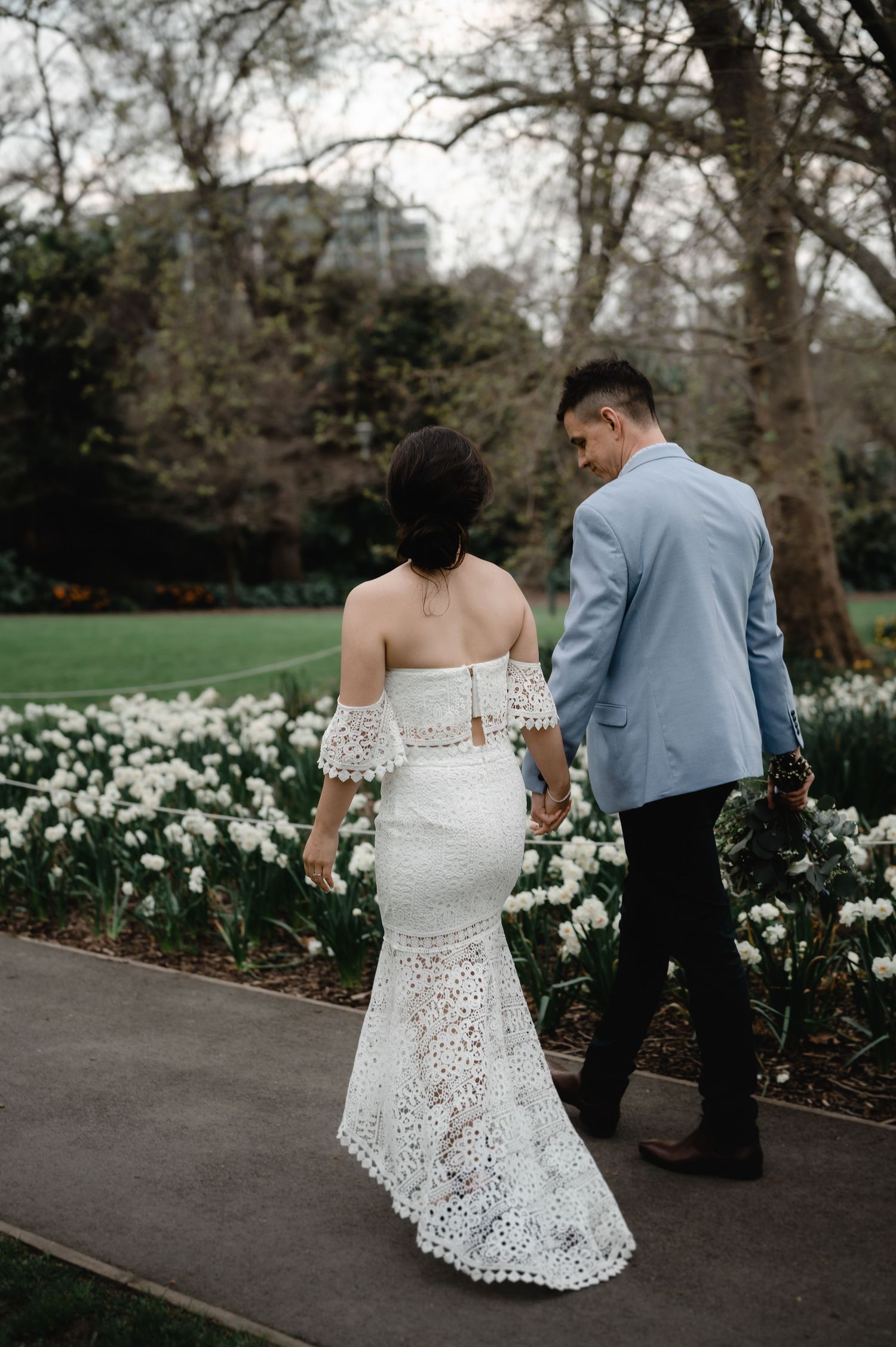Couple walking through garden path lined with white daffodils.