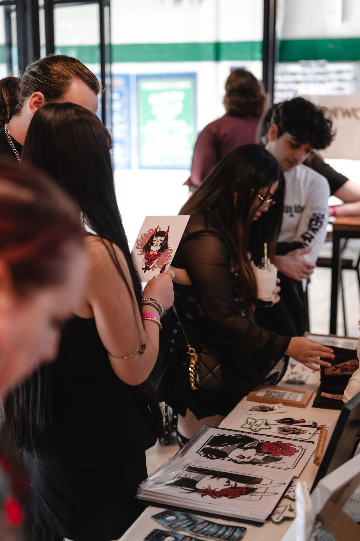 People sit at tables signing autographs and interacting with fans at a meet and greet event.