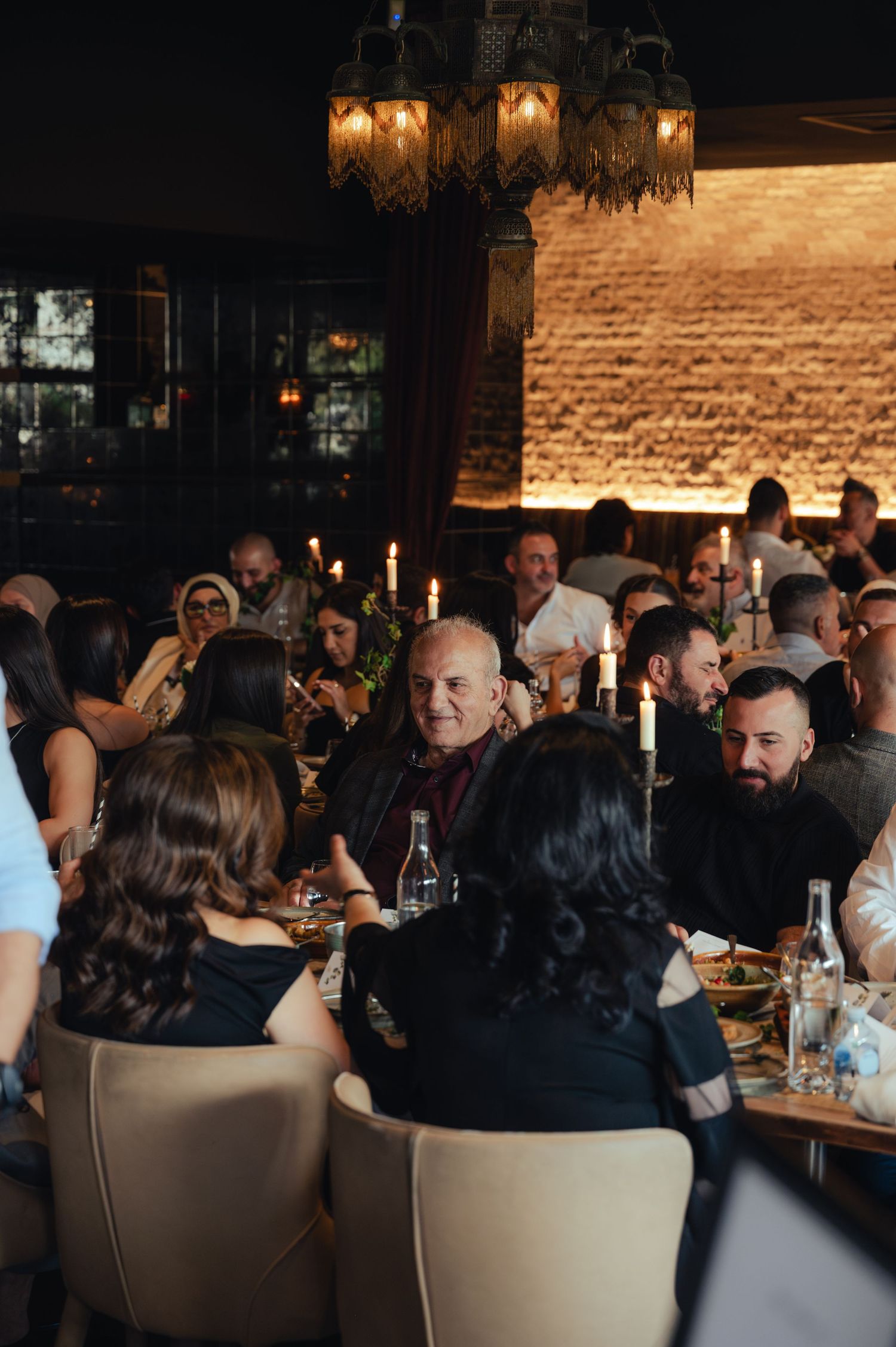 Guests dining at an elegant candlelit restaurant during a formal evening gathering.
