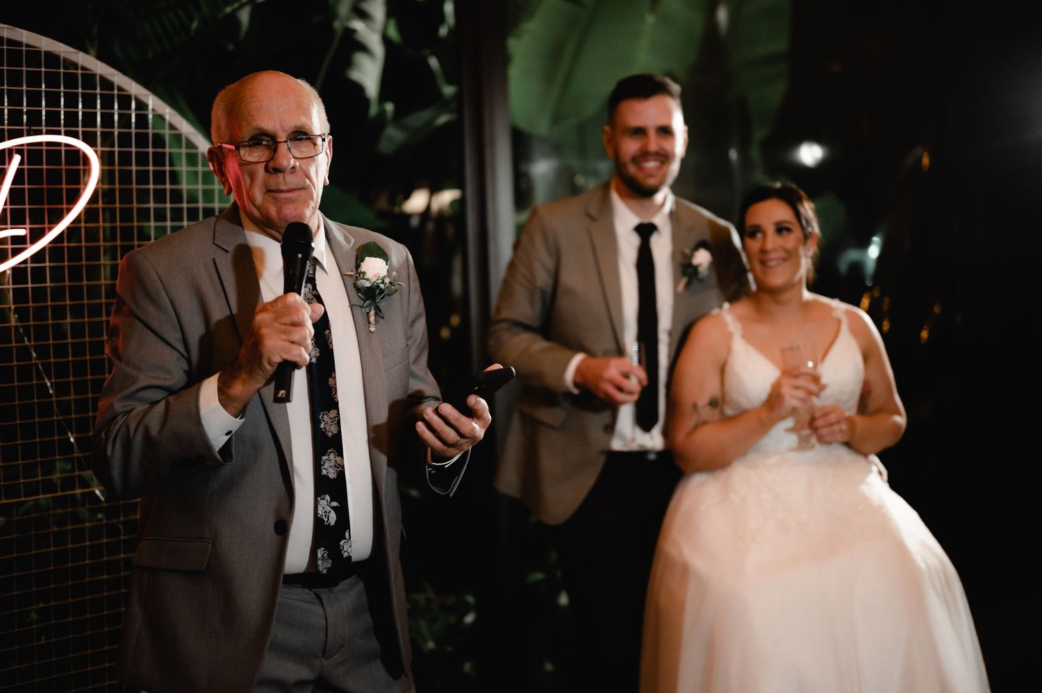 Wedding reception guests gather under dim lighting with red neon accents.