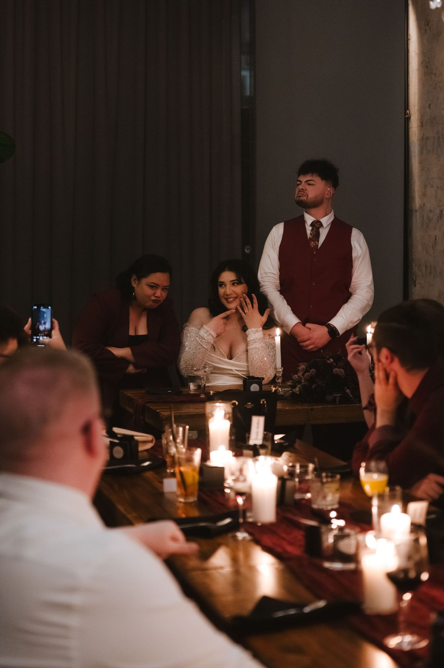 Wedding reception dinner scene with candlelit tables and guests in formal attire.