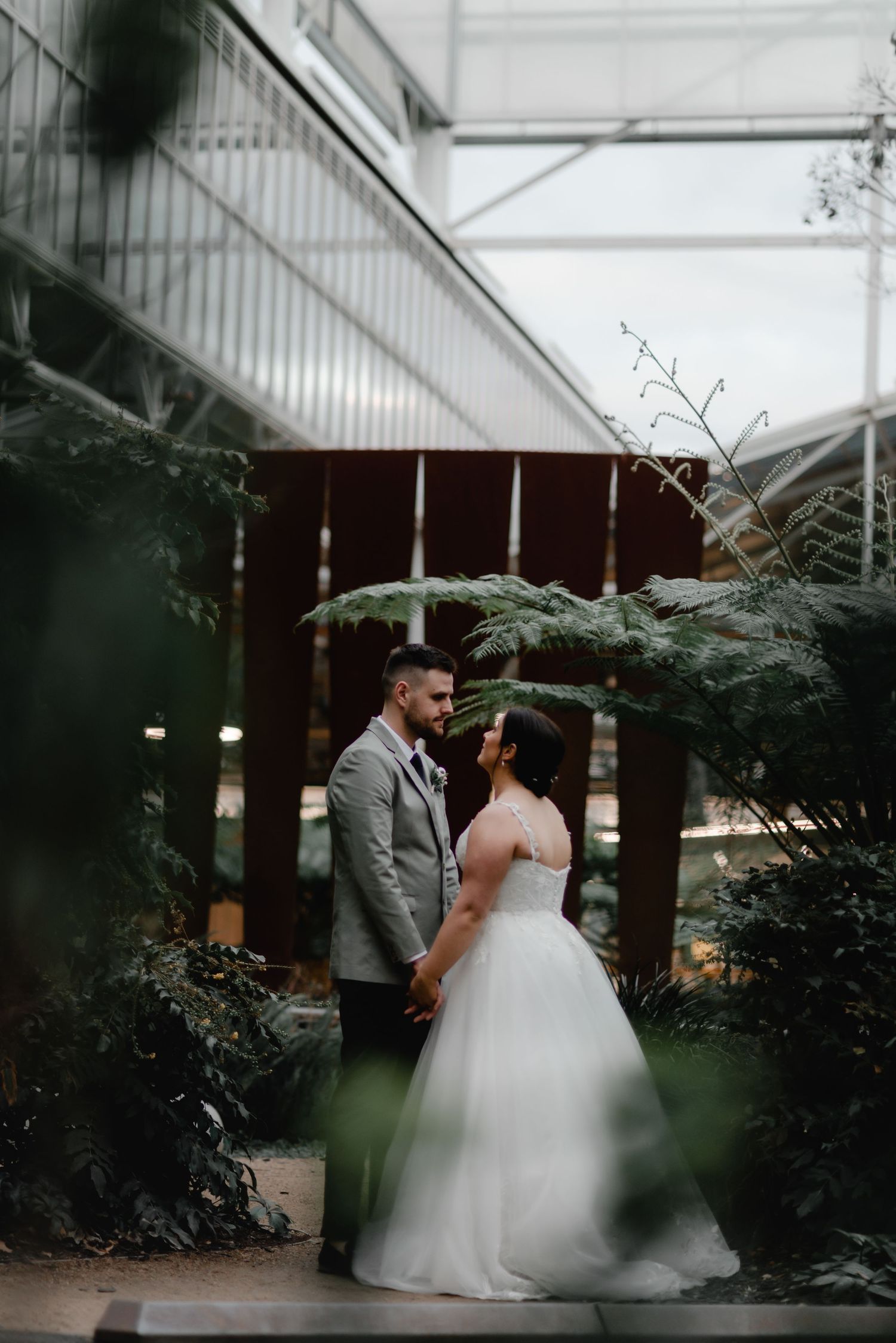 Couple shares intimate moment among indoor greenery and ferns.