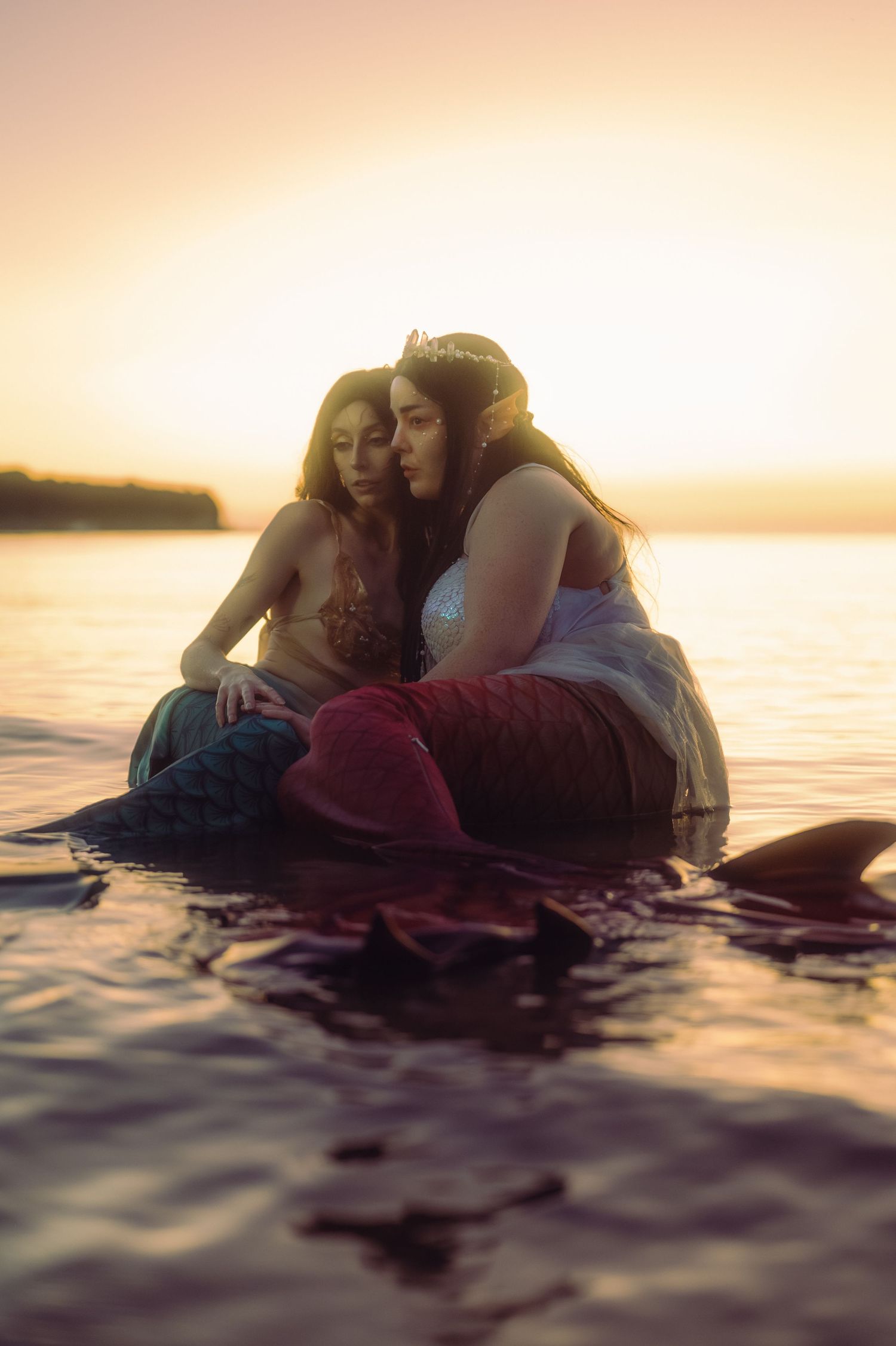 Couple embracing in ocean water during golden sunset creating romantic silhouette.