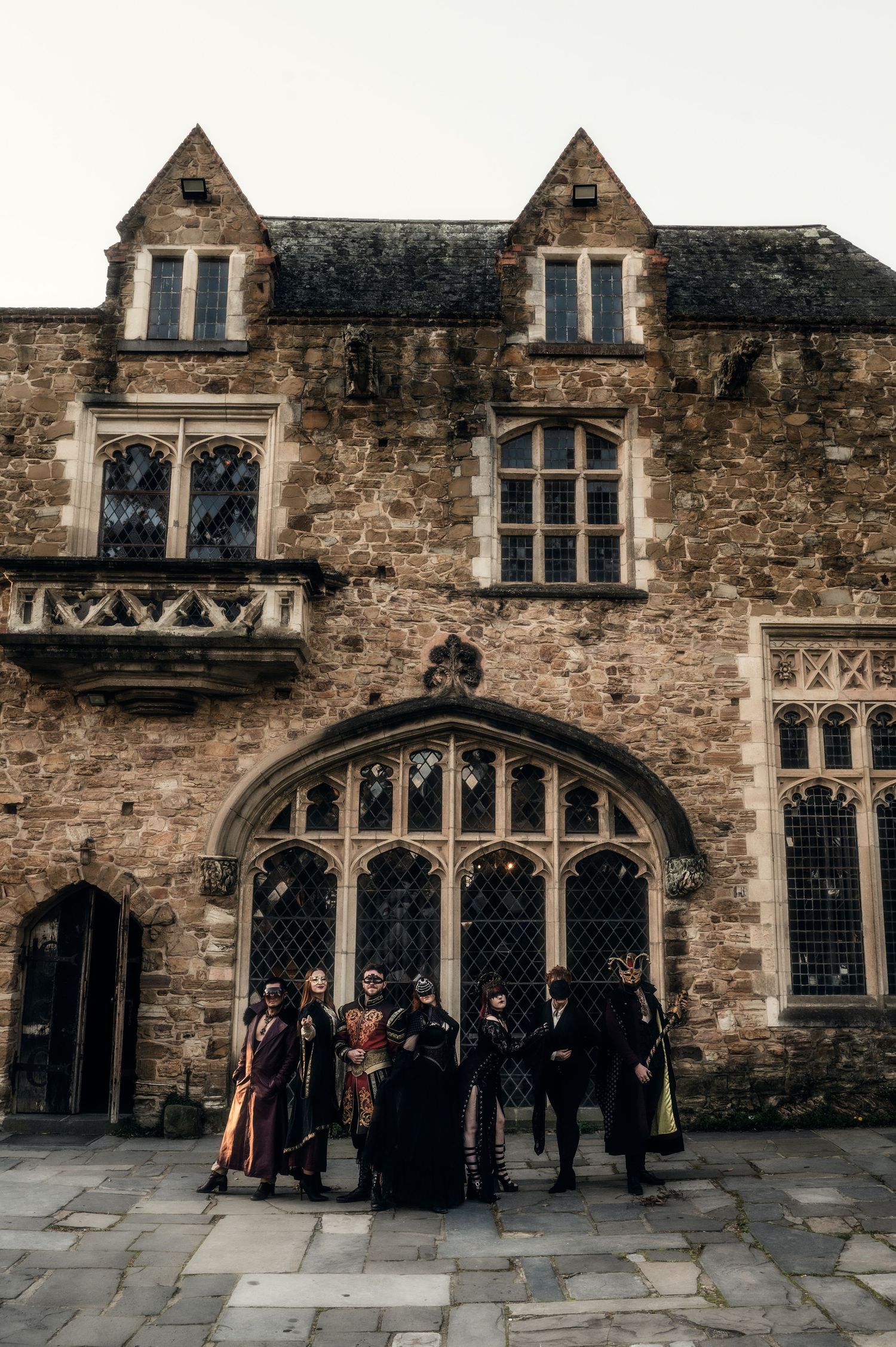 Group gathered outside a historic stone building with gothic architecture and arched windows.