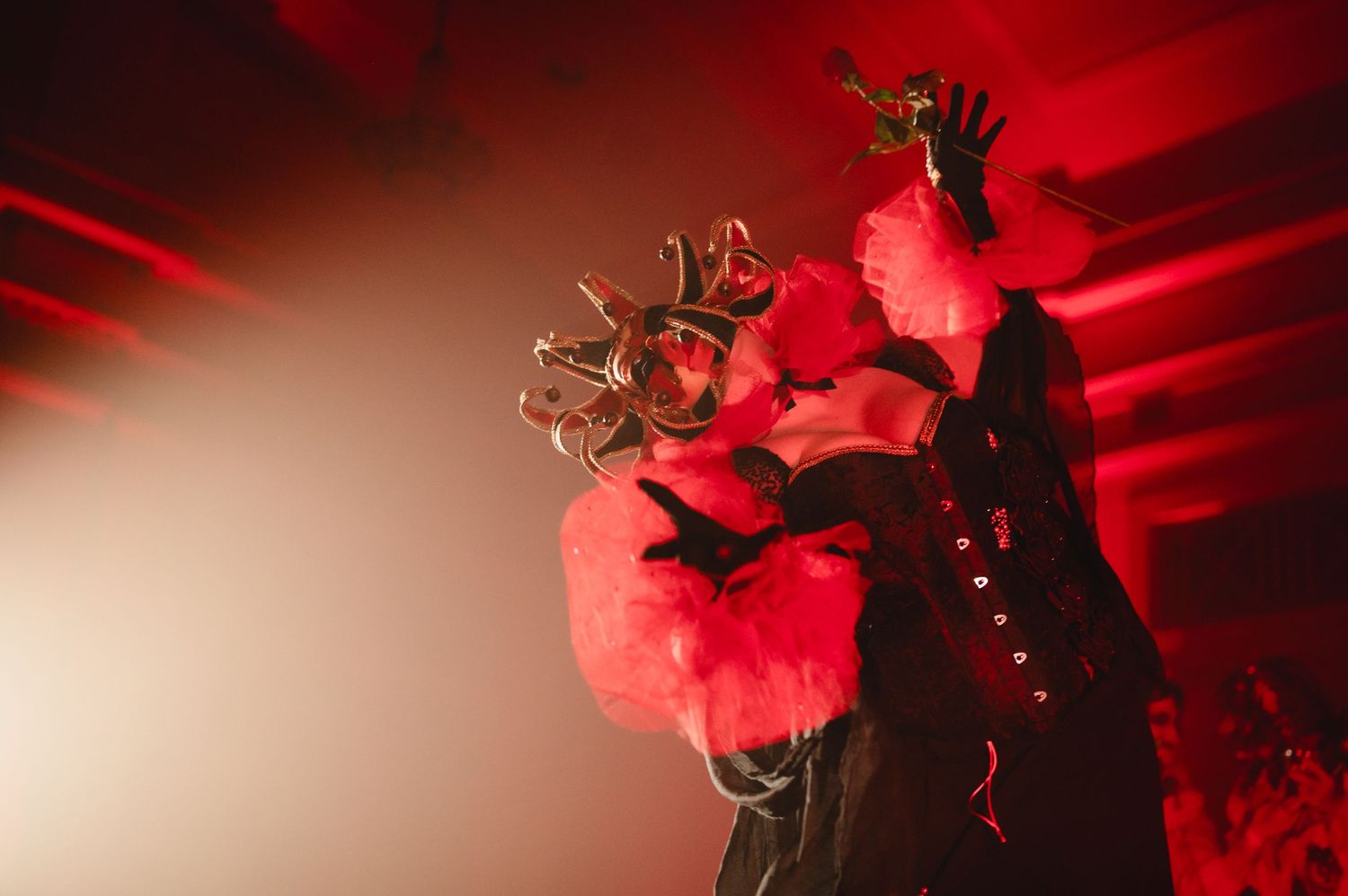 A performer silhouetted against dramatic red stage lighting and smoke effects during a concert performance.