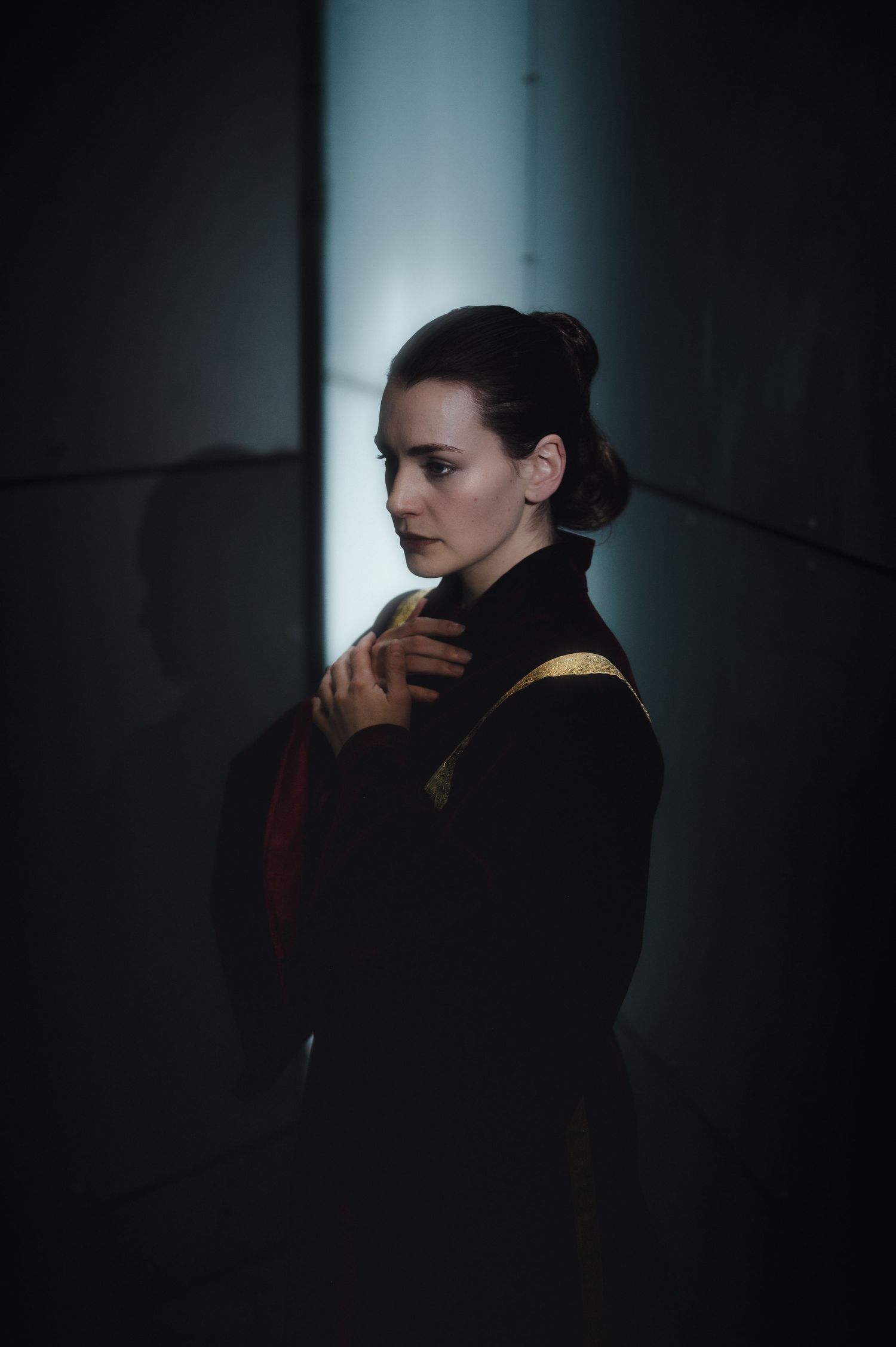 Atmospheric portrait in shadows with dramatic lighting and dark clothing.