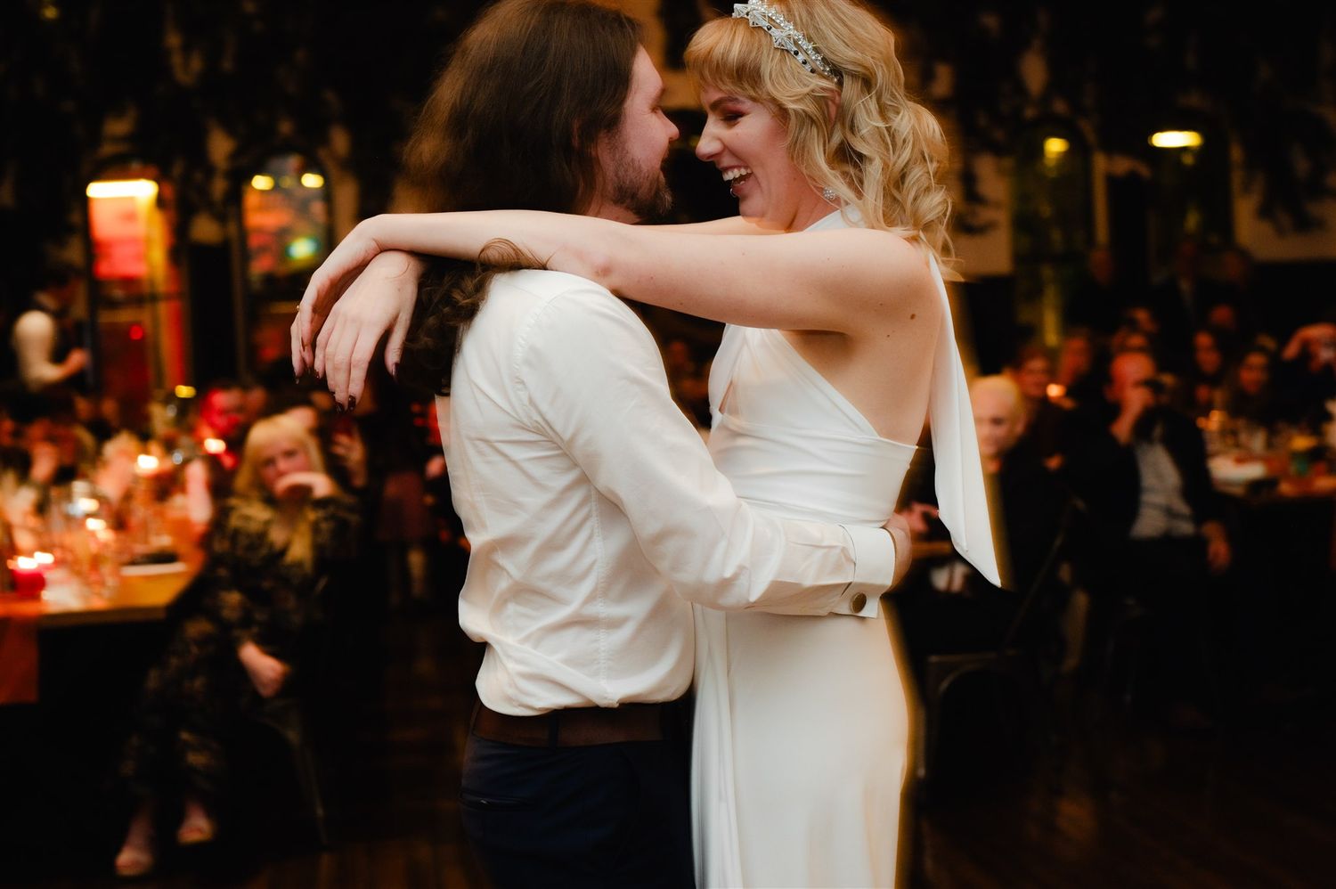 Wedding reception dance floor filled with couples dancing in warm ambient lighting.