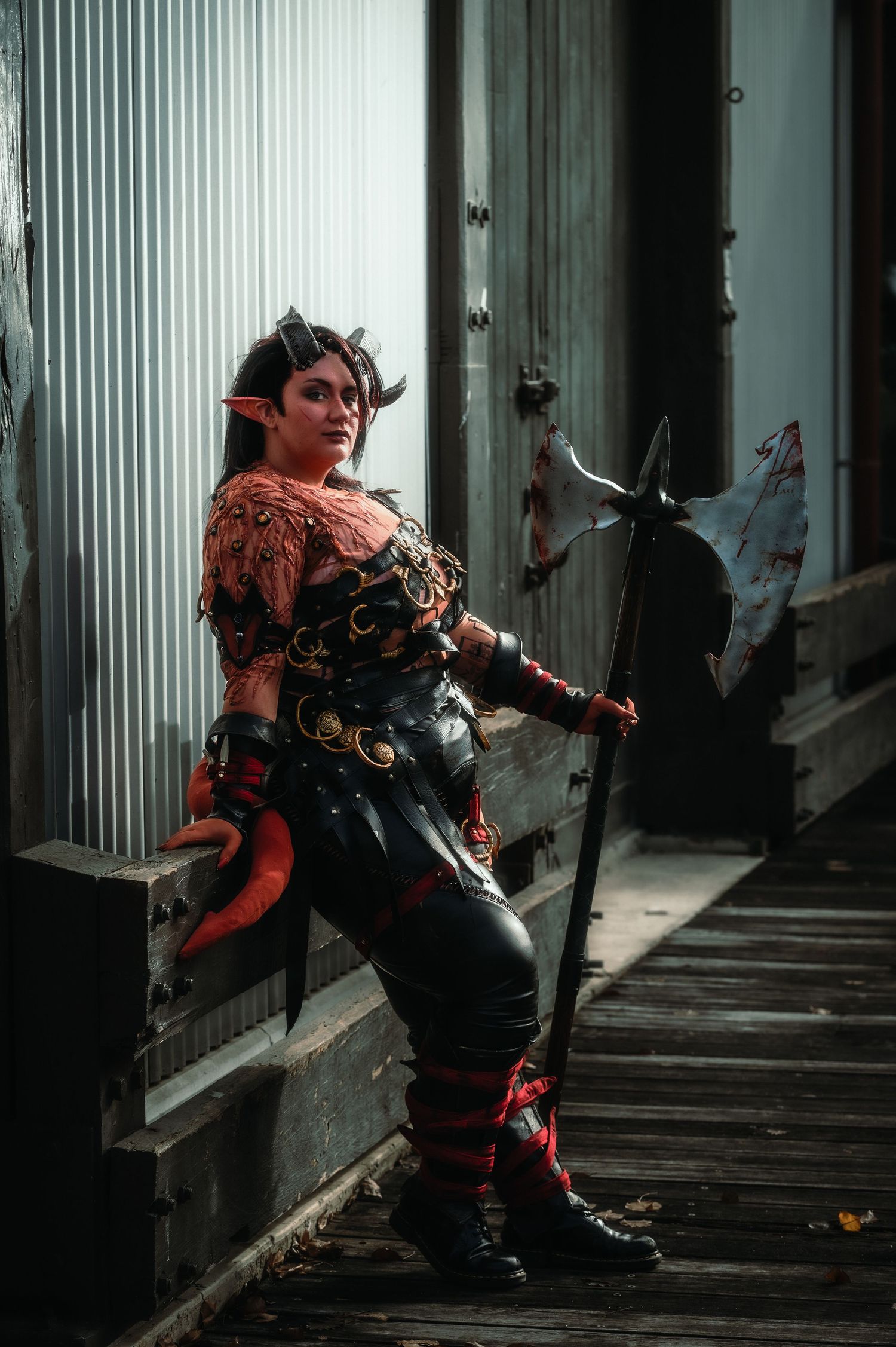 Dramatic cosplay photography featuring ornate red and black costume in shadowy corridor.