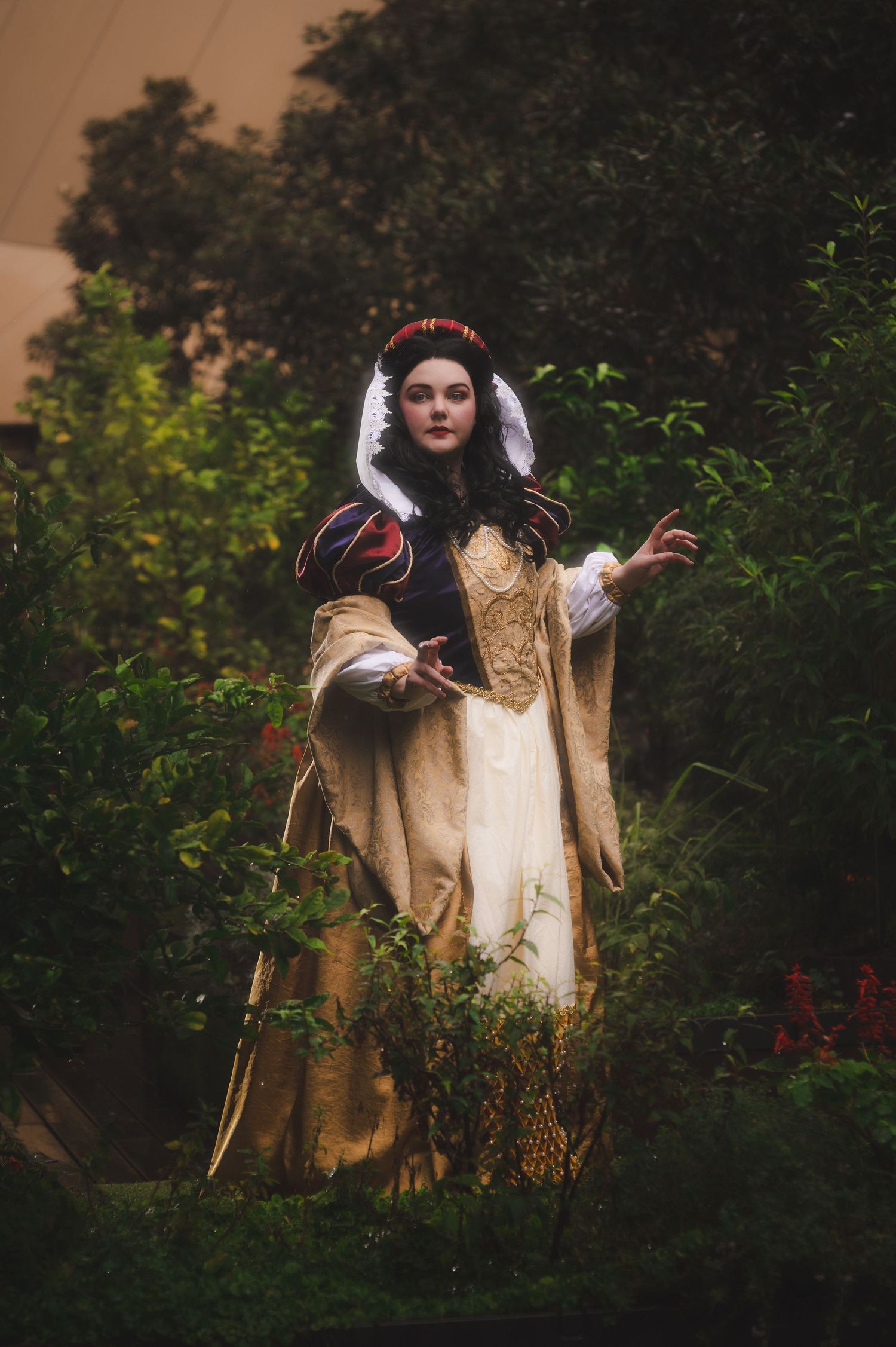 Renaissance costume photography in lush garden with dramatic lighting.