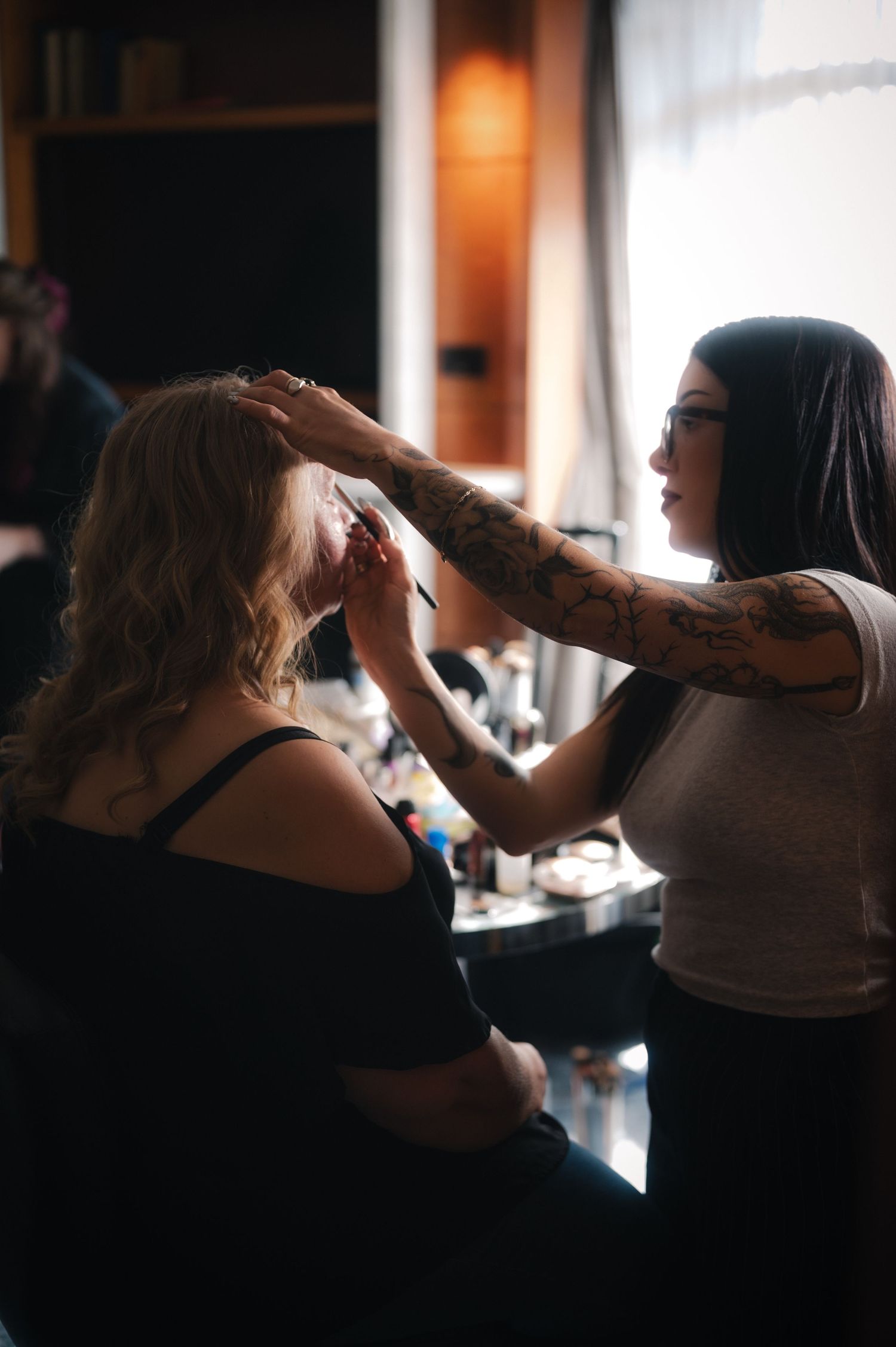Silhouettes of people getting ready in a room with natural window light.