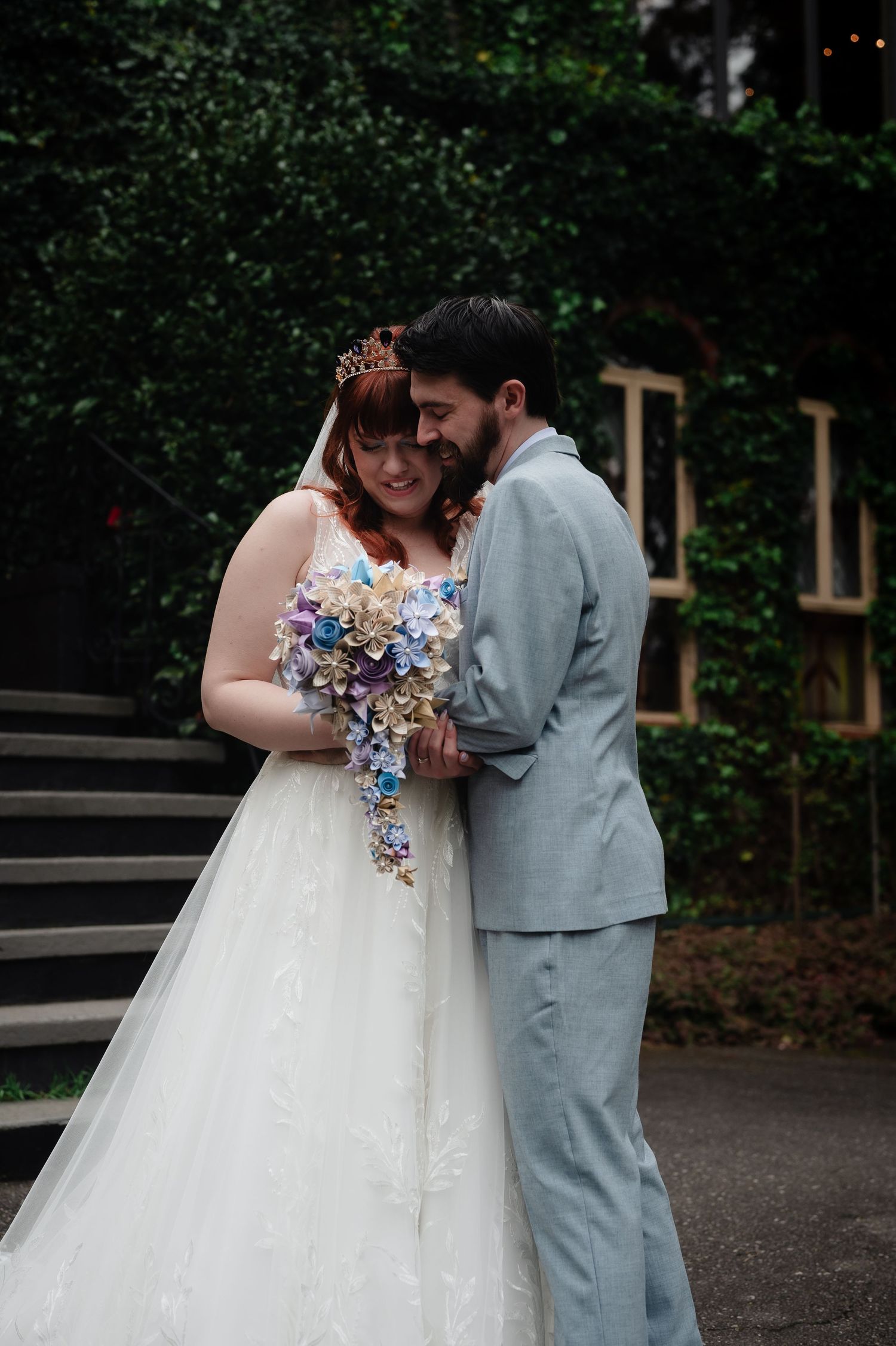 Couple admires colorful wedding bouquet during intimate outdoor photo session.
