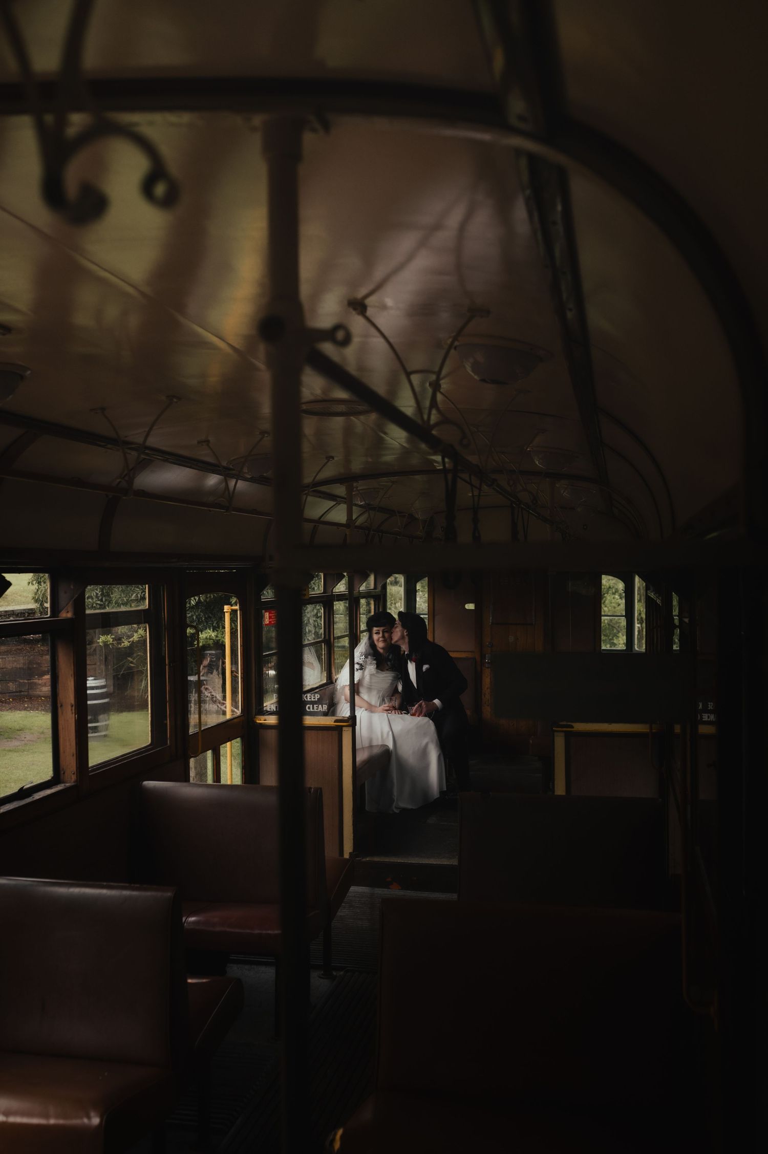 Bride and groom share an intimate moment inside a vintage tram during their wedding day.