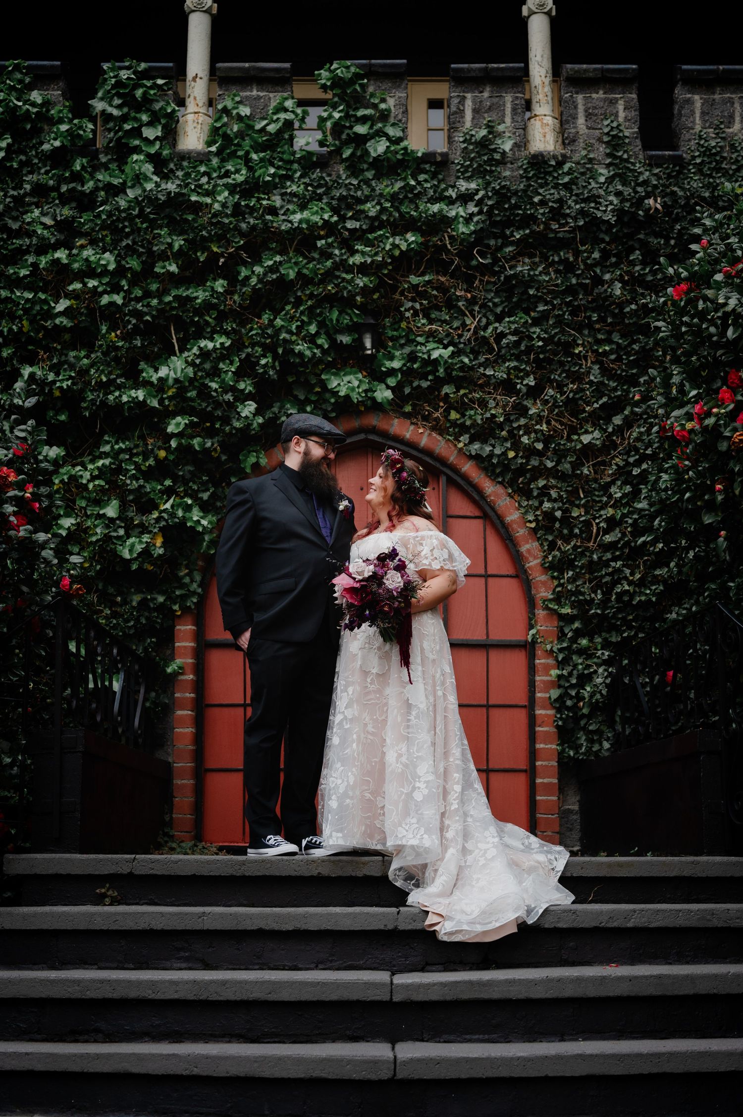 Romantic wedding portrait with ivy-covered archway and stone steps.