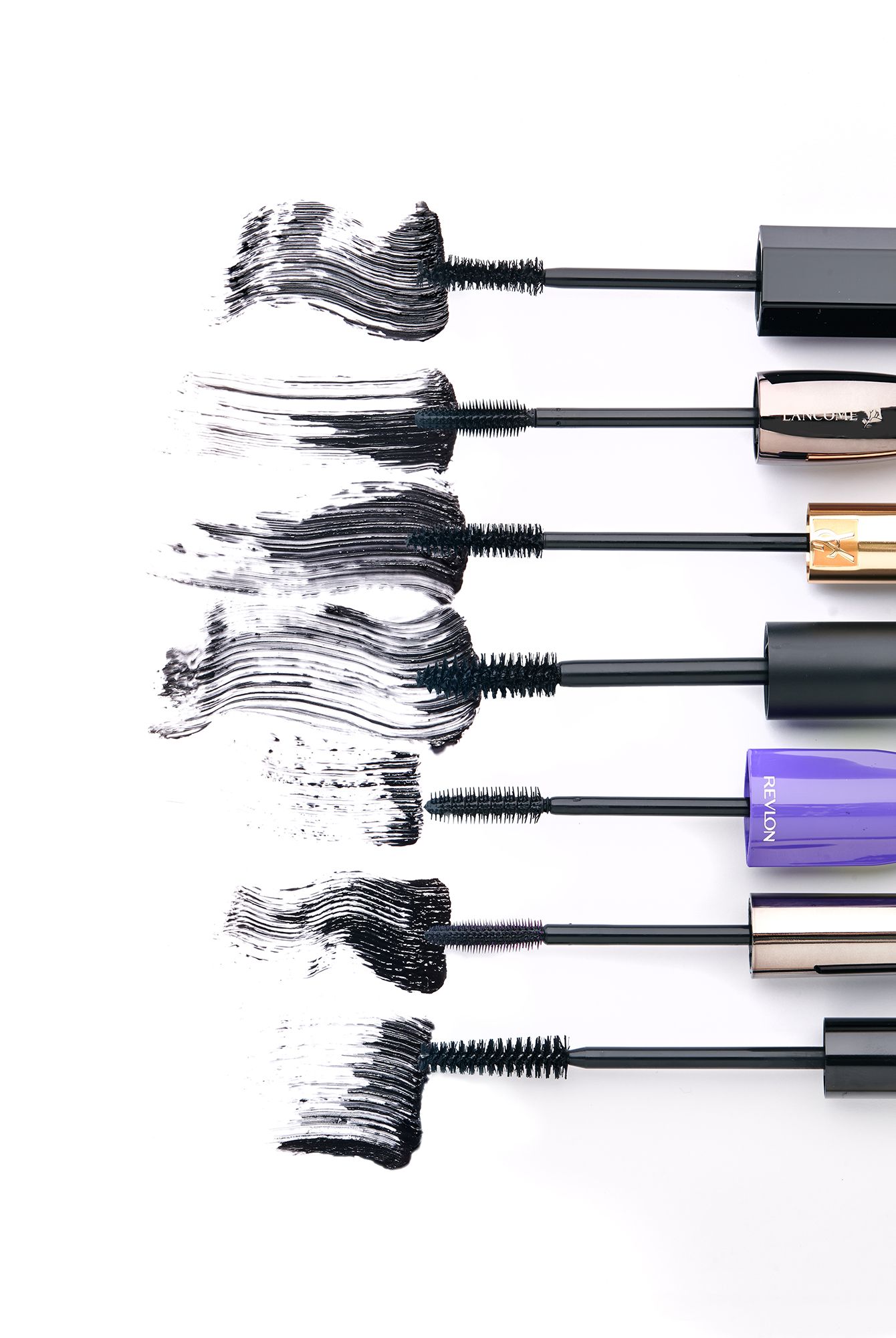 Five mascara wands with black product swatches on white background, showcasing different brush types and formulas.